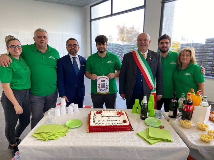 Un gruppo di persone in piedi attorno a un tavolo con sopra una torta