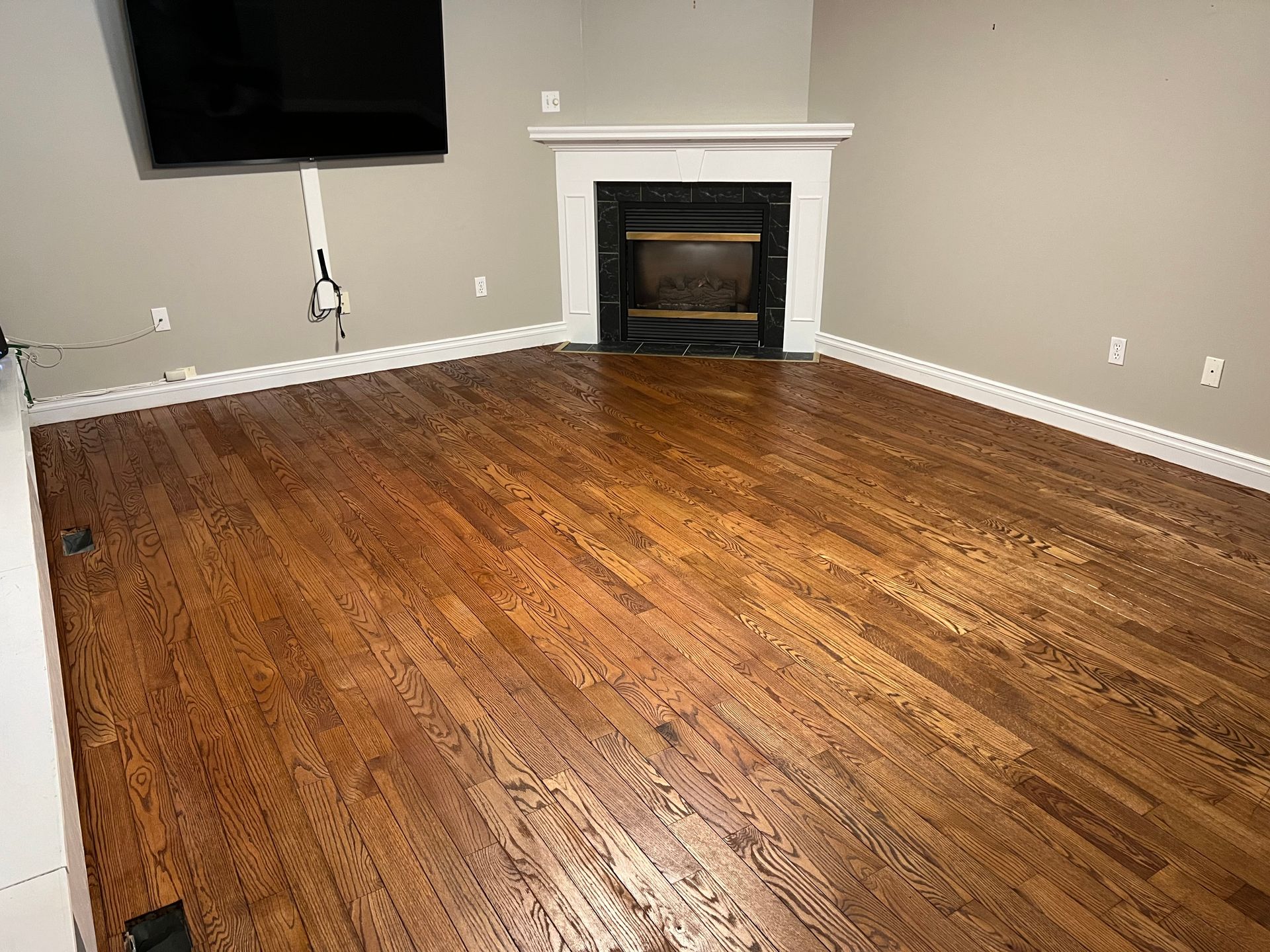 A room with hardwood floors, a fireplace, and a mounted TV.