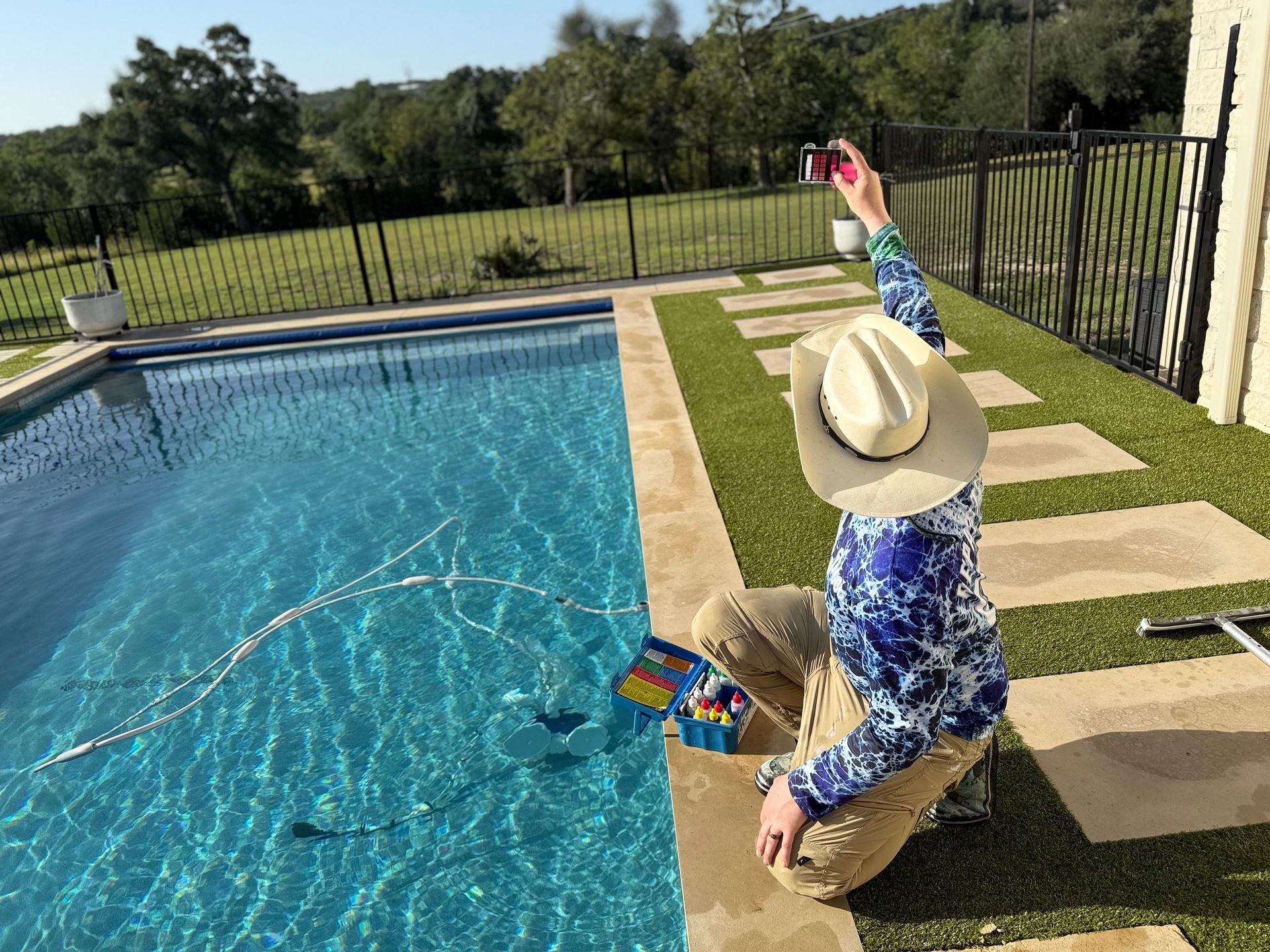 Person with cowboy hat taking photo by pool.