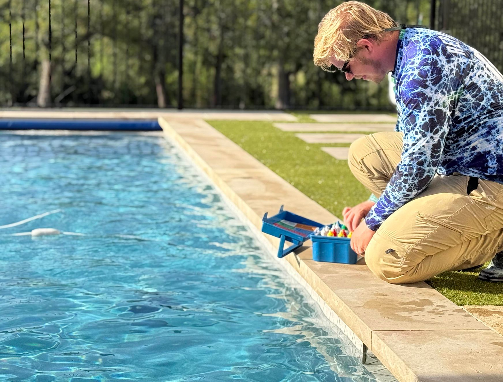 Man checks pool water with kit at poolside.