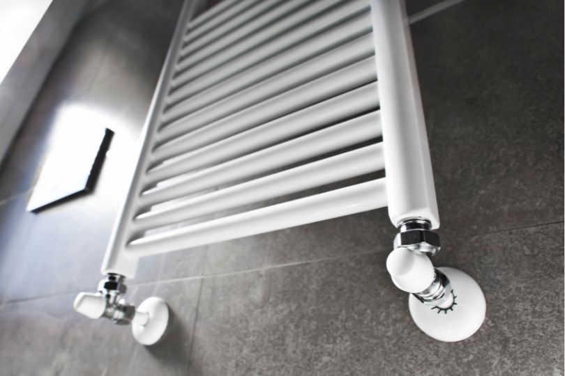 A modern bathroom radiator, attached to a wall, made out of grey tiles.