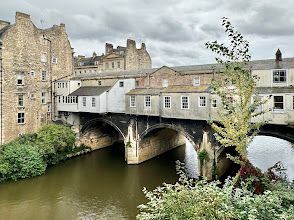 A bridge over a river in a city with buildings in the background.