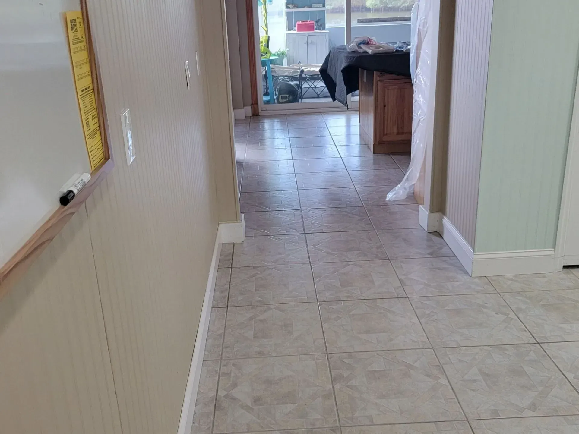 Hallway with tile floor, off-white walls, and a view to an outdoor space.