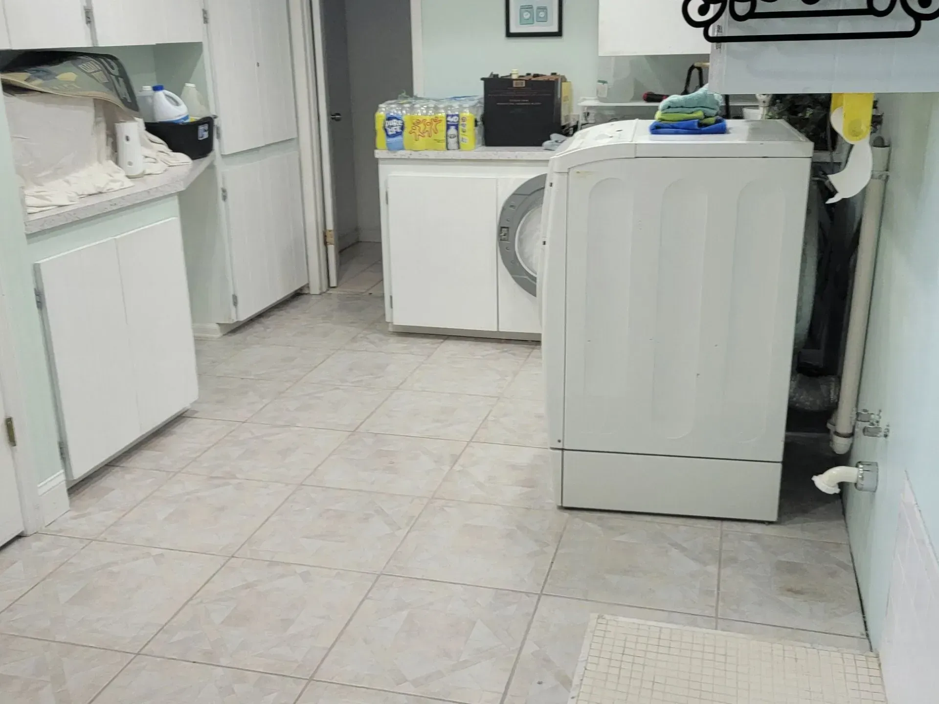 Laundry room with white appliances, tiled floor, and cleaning supplies.