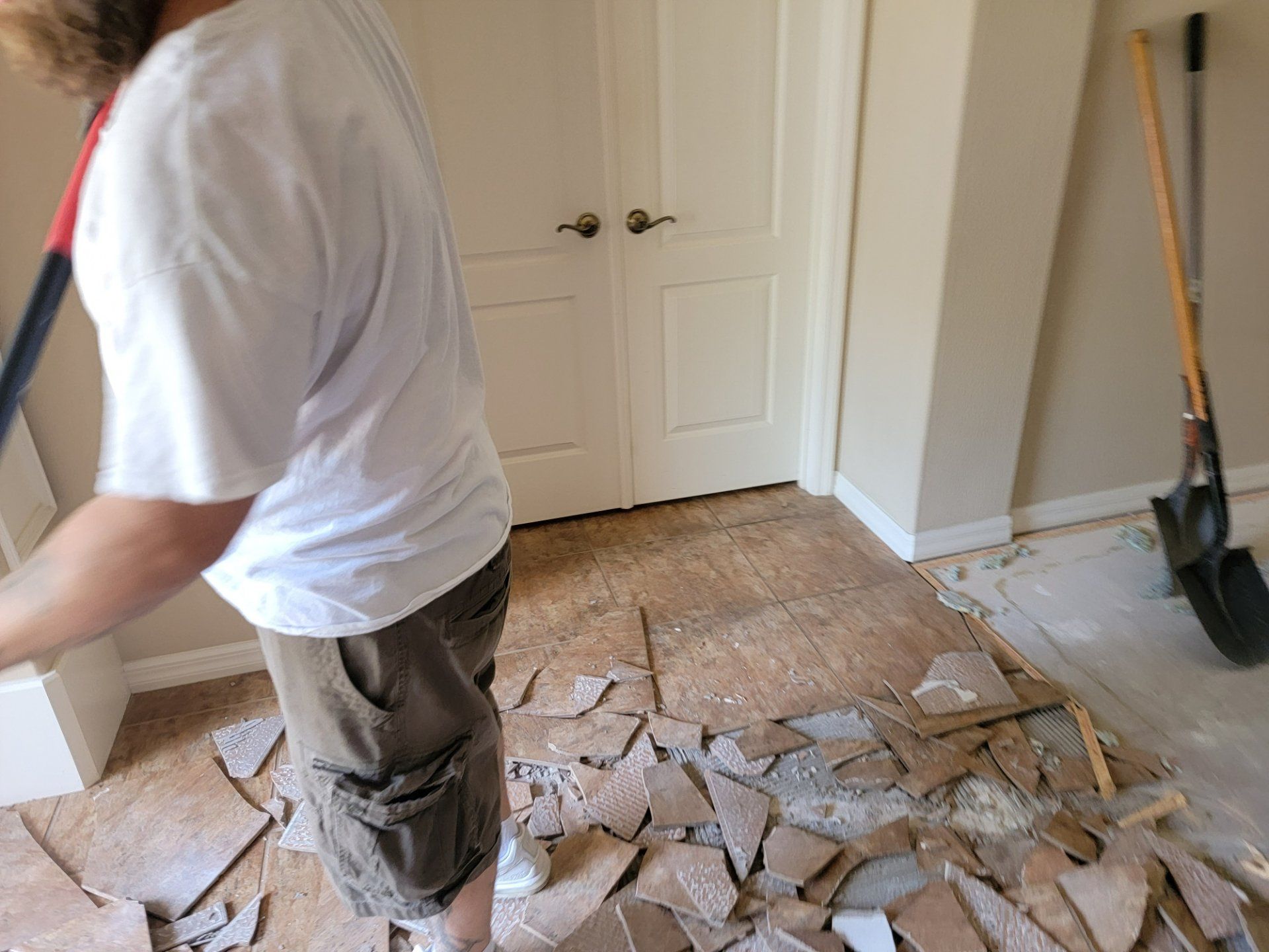 A man is standing in a room with a shovel in his hand