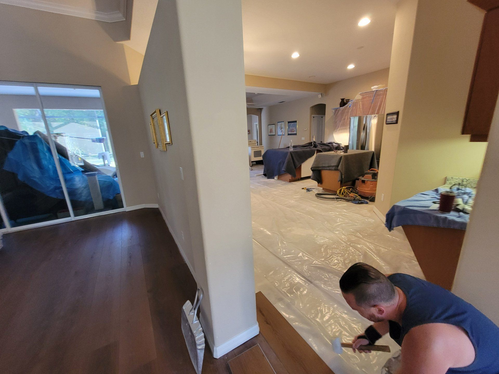 A man is working on a wooden floor in a living room.