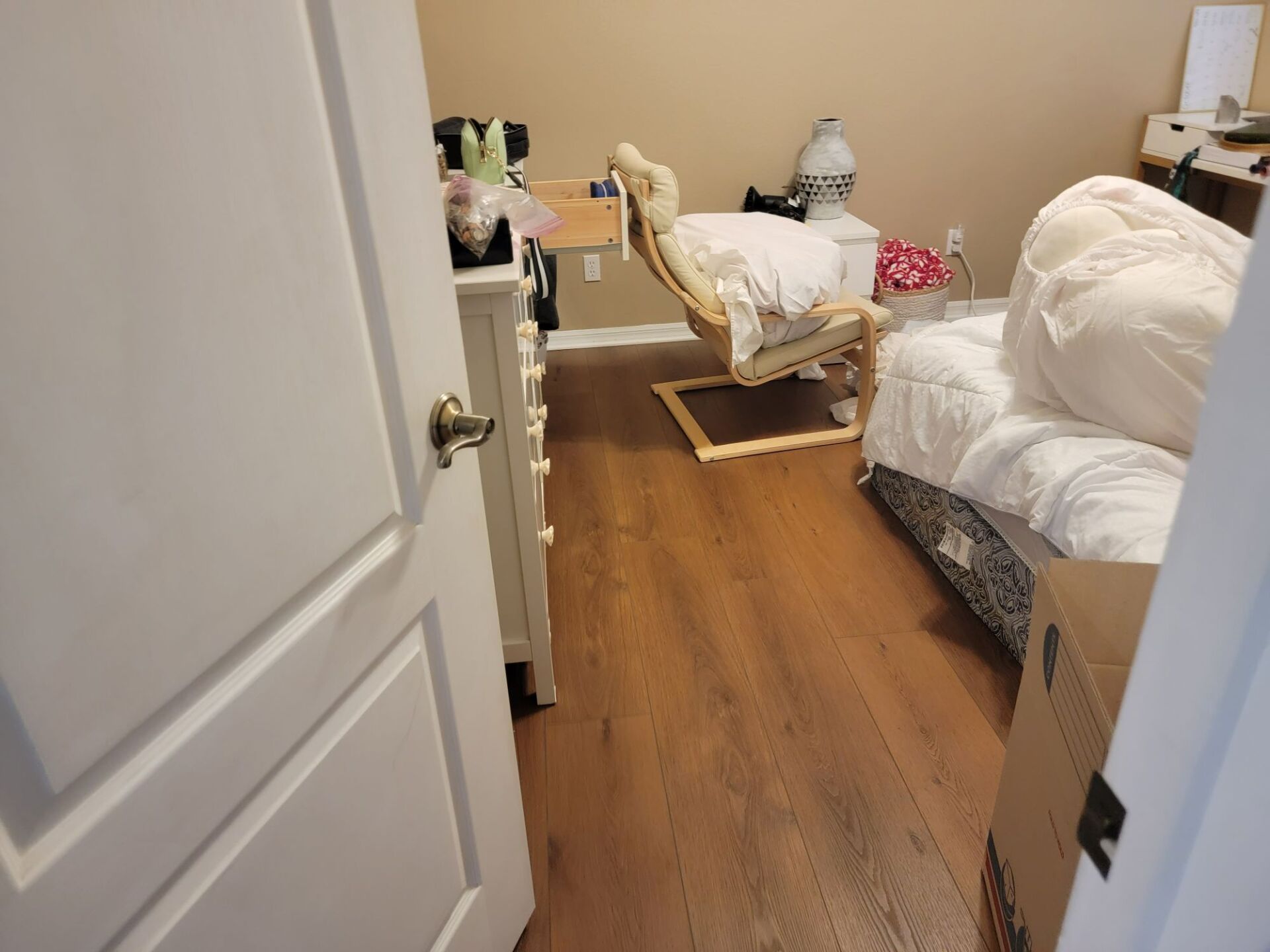 A bedroom with hardwood floors , a chair , a bed and a dresser.