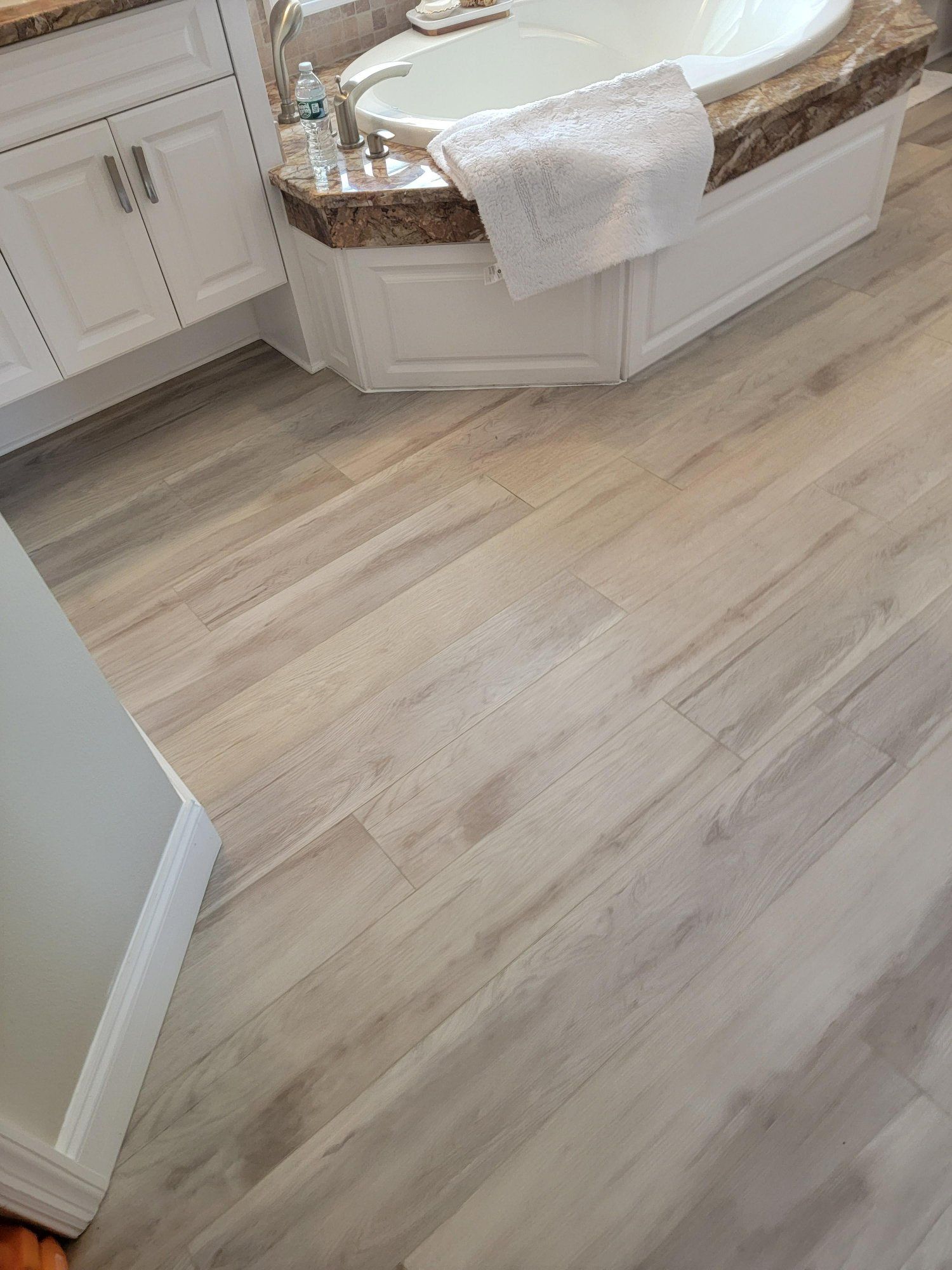 A bathroom with a bathtub and a wooden floor.