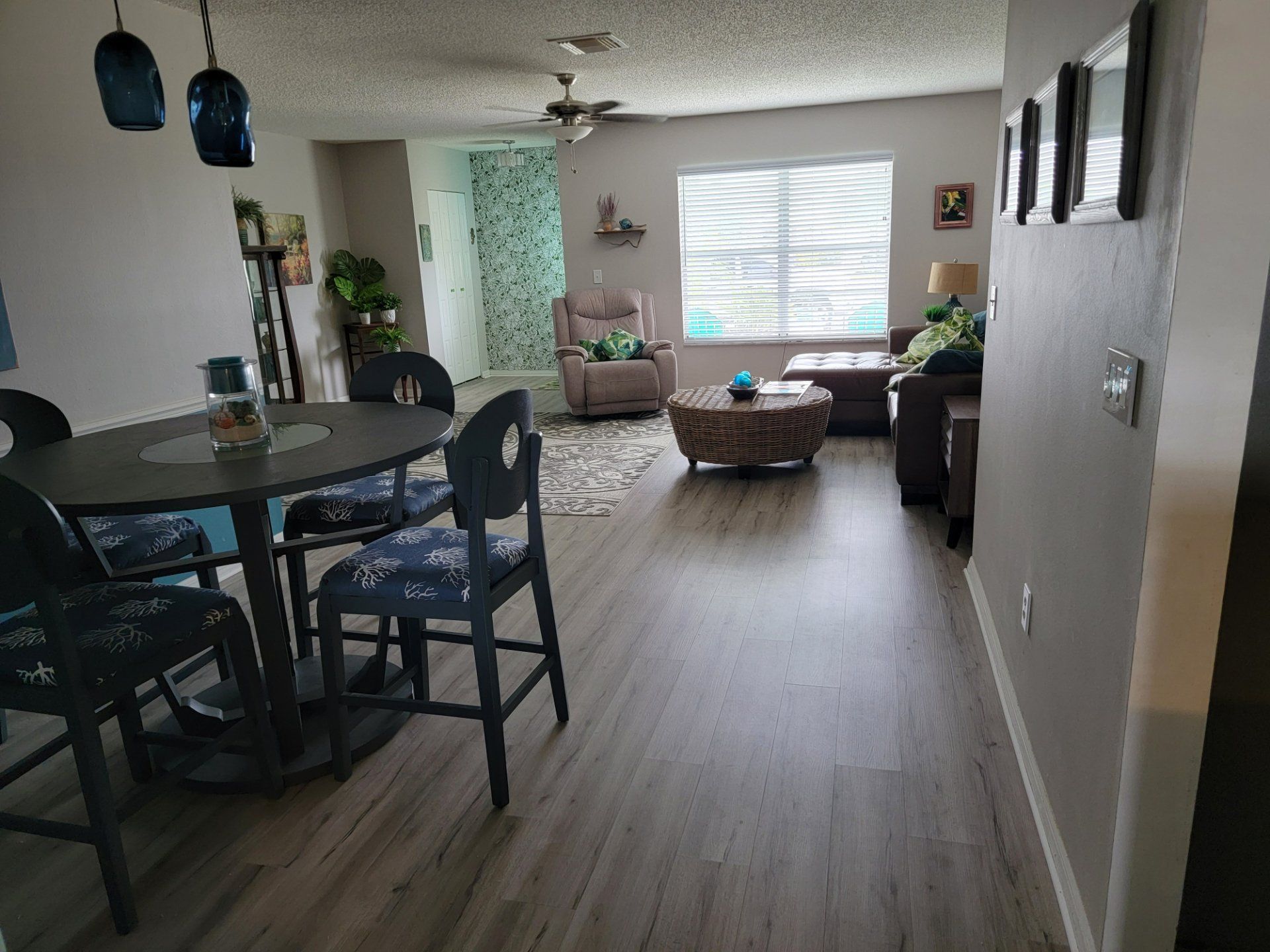 A living room with a table and chairs and a ceiling fan.