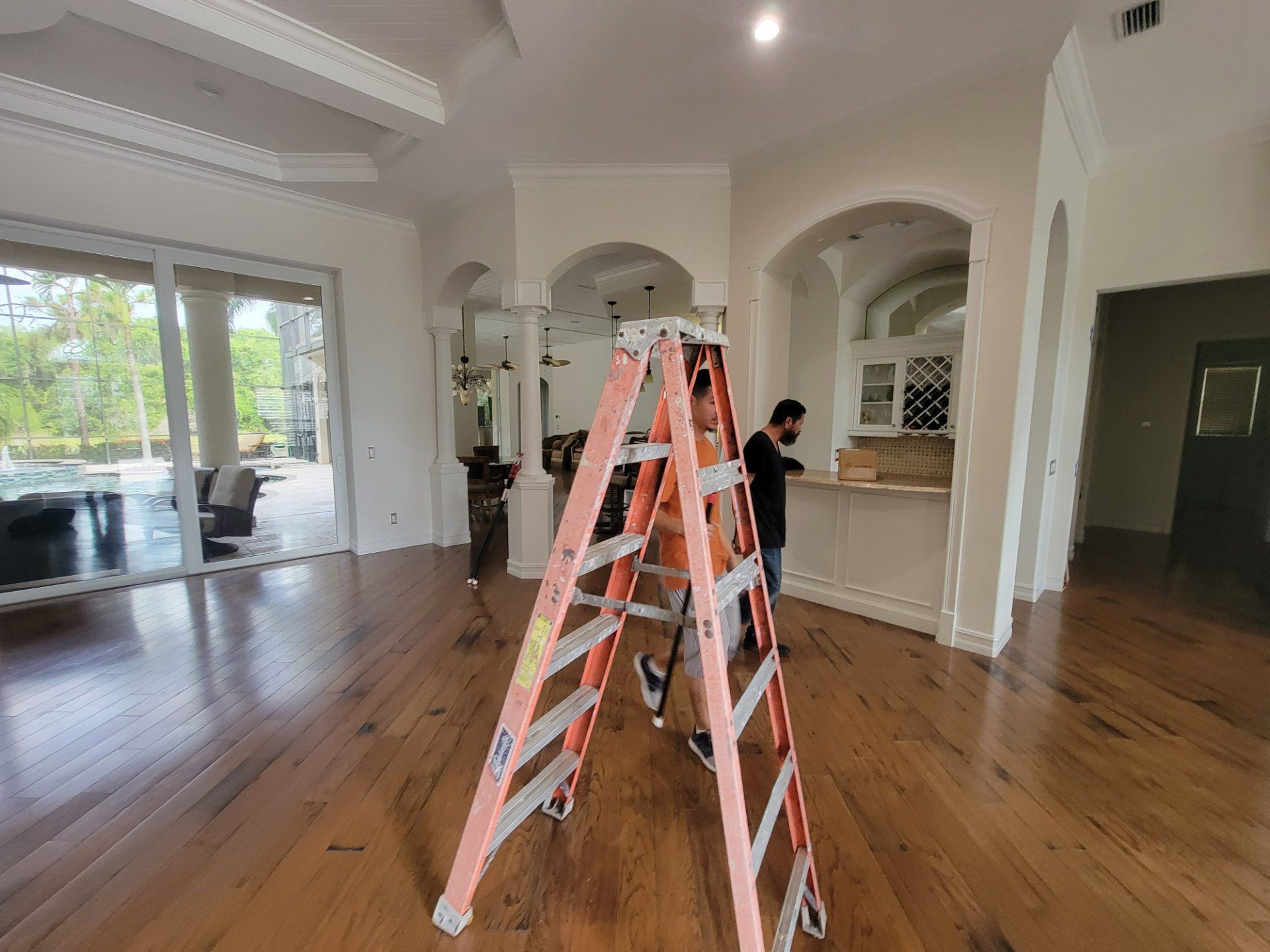 A man is standing on a ladder in a living room.