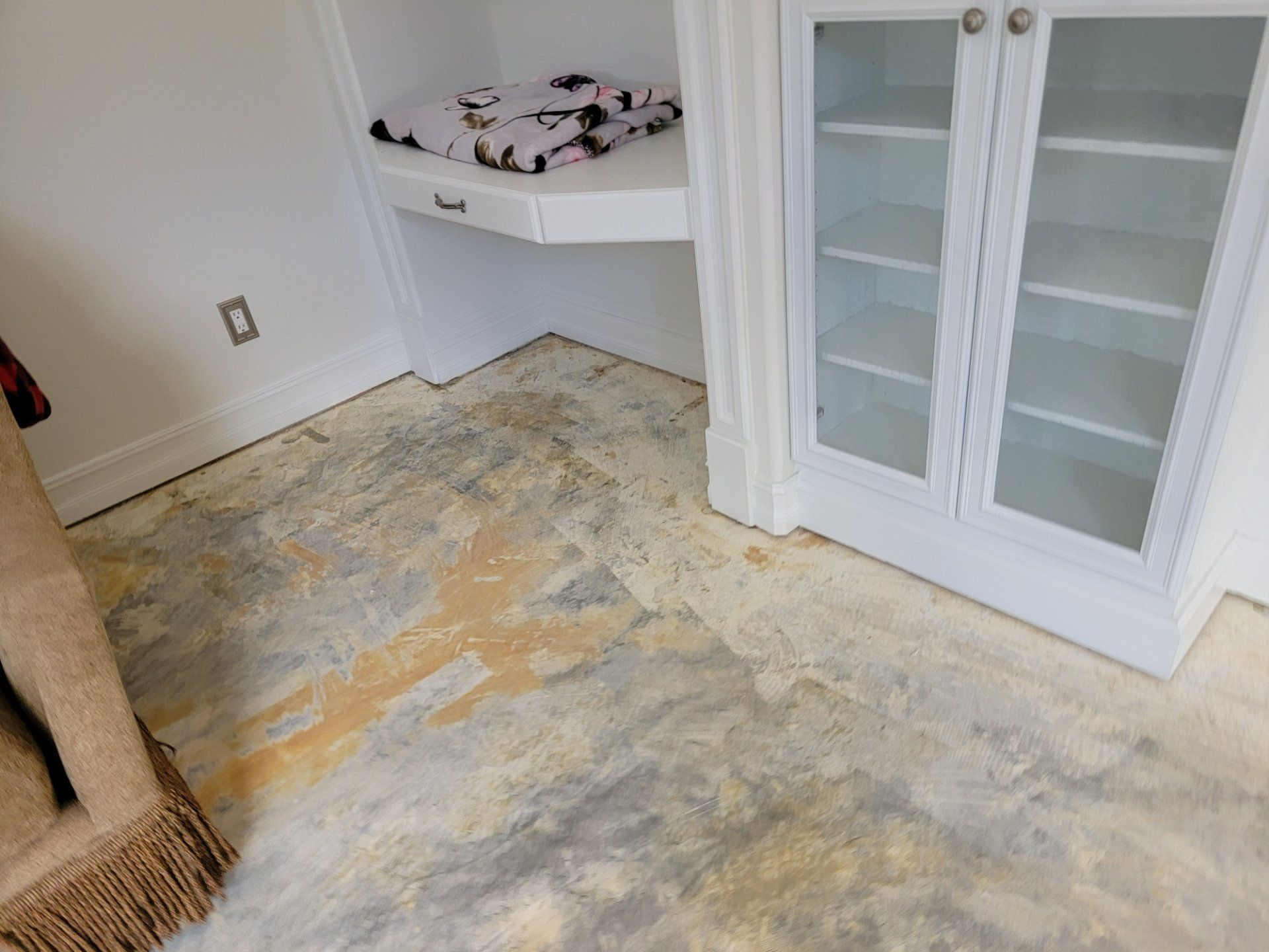 A dirty floor in a room with a desk and cabinets.