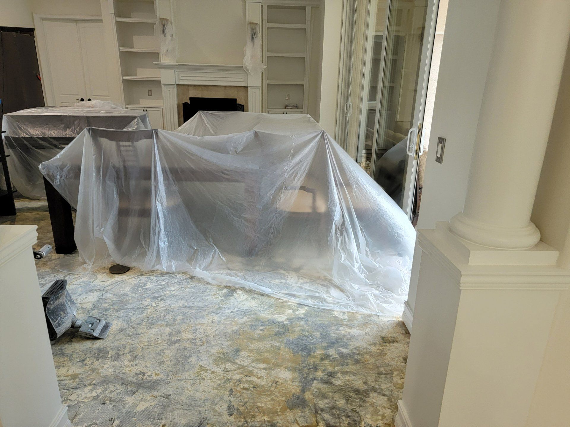 A room with a table and chairs covered in plastic.