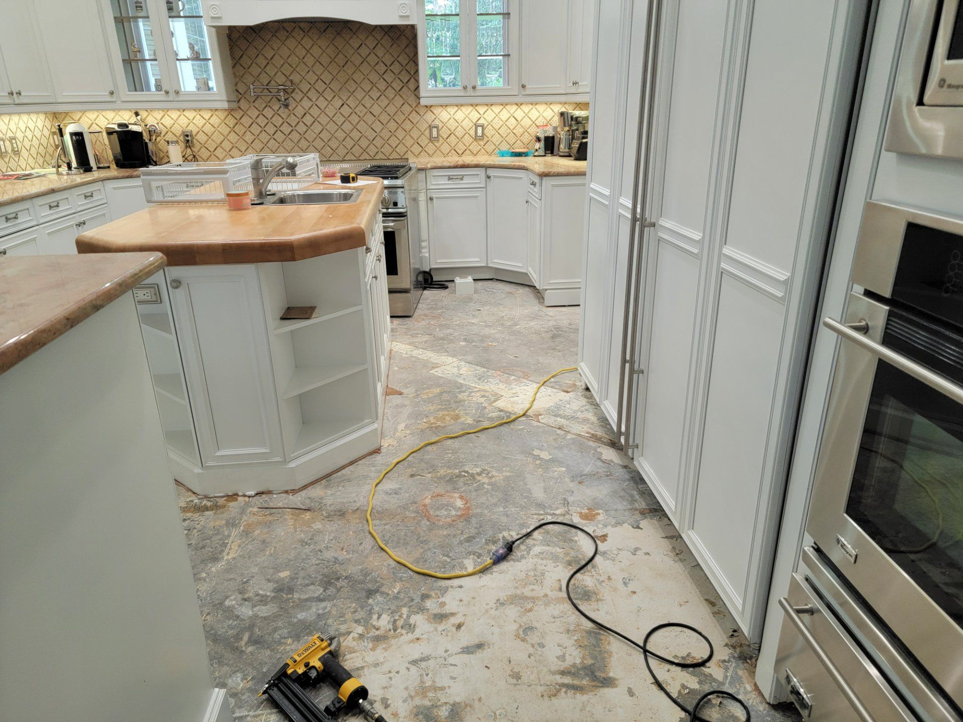 A kitchen with white cabinets and stainless steel appliances is being remodeled.
