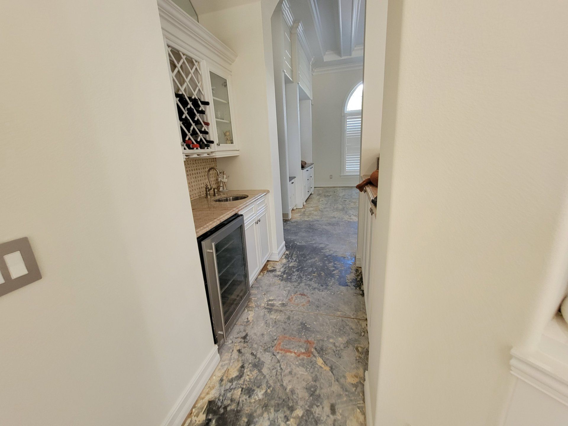 A hallway in a house with a wine cooler and a sink.