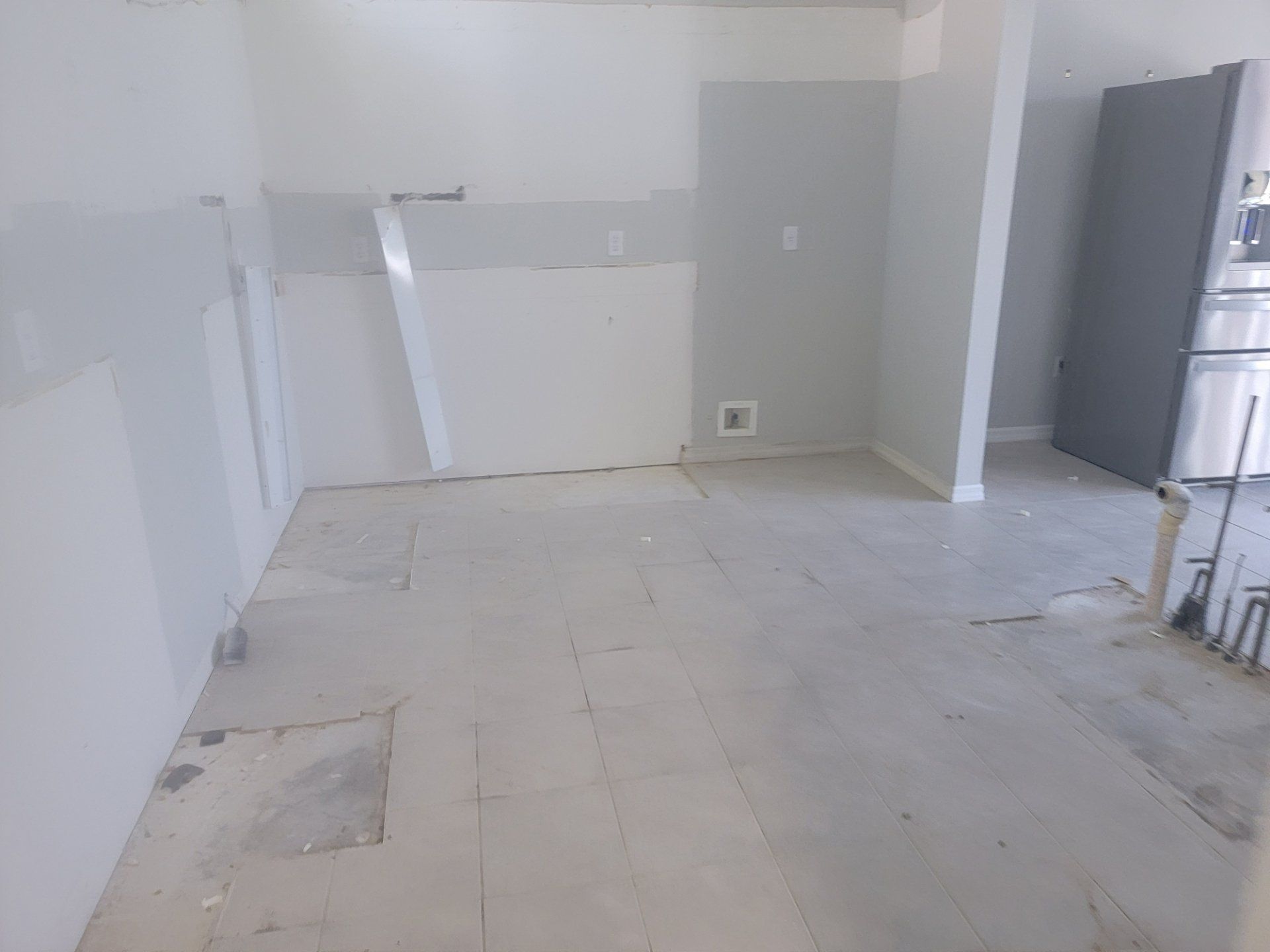 An empty kitchen with a refrigerator , dishwasher , and stove.