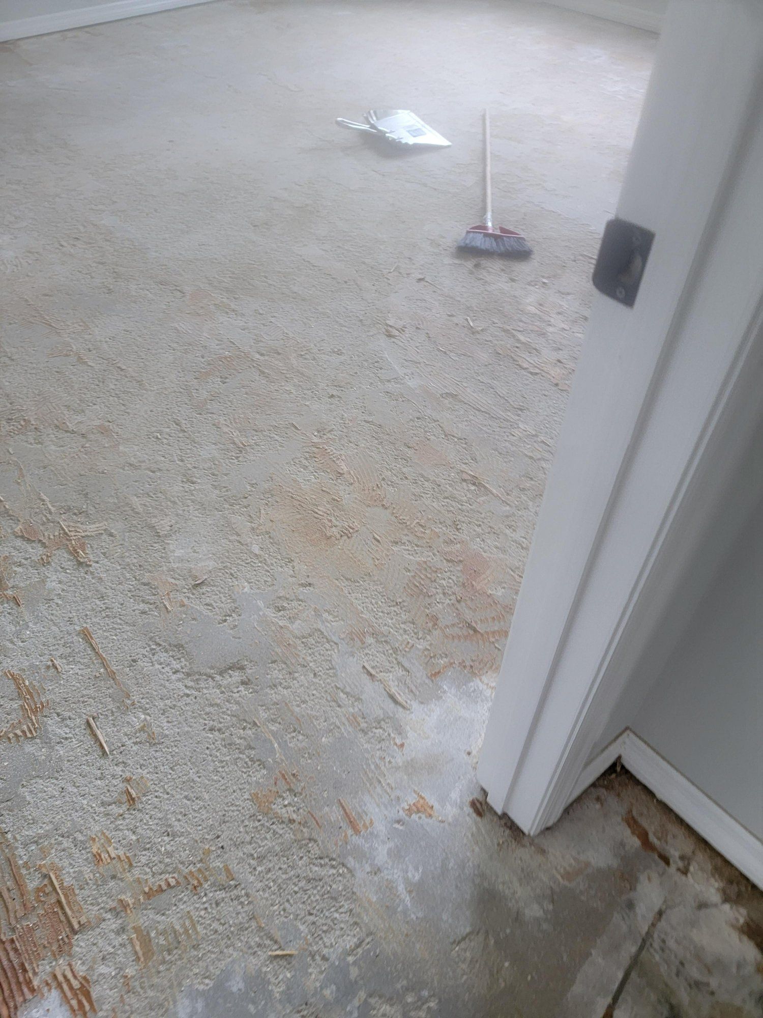 A room with a door and a broom on the floor.