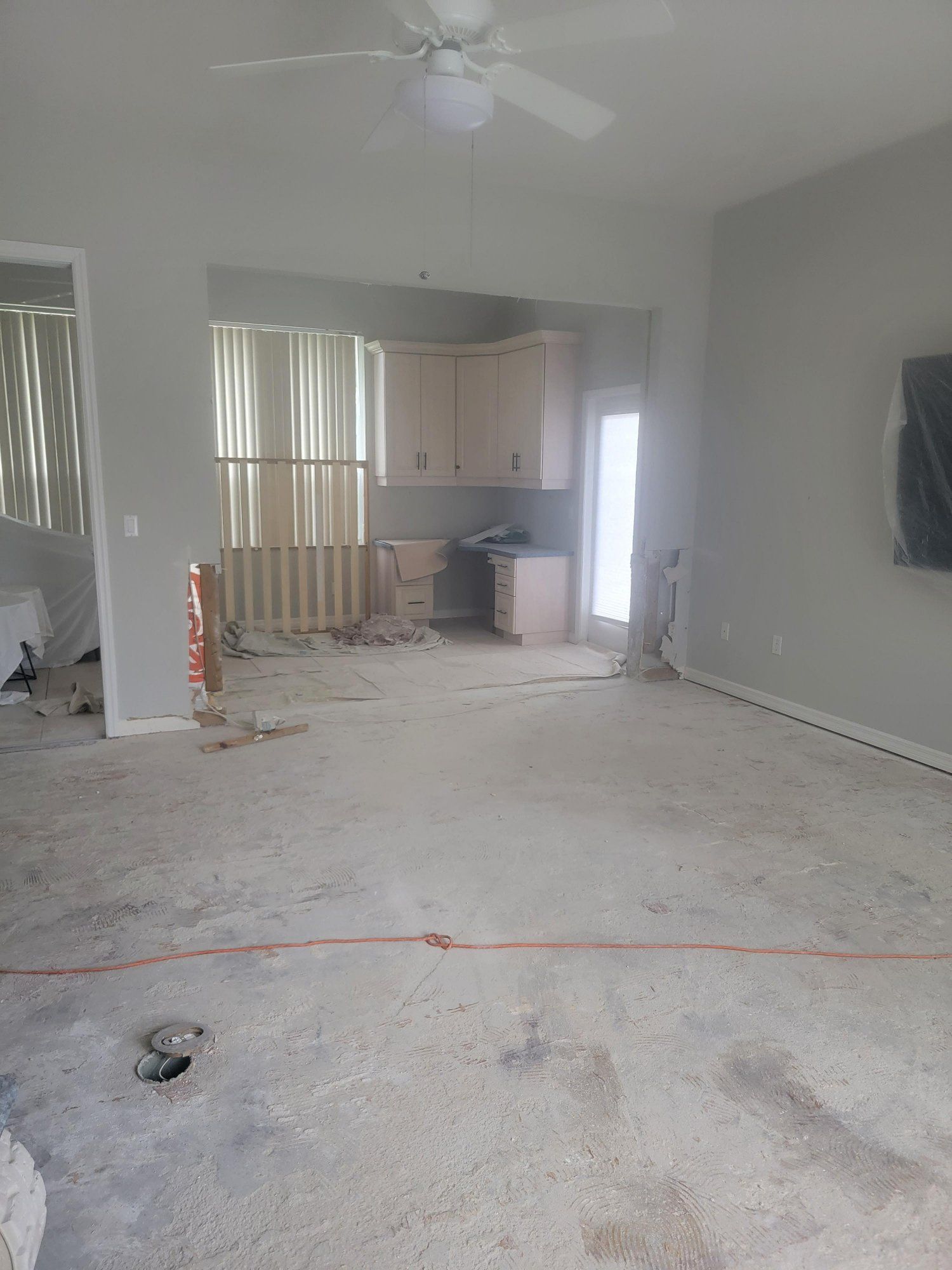 A living room with a ceiling fan and a dirty carpet.