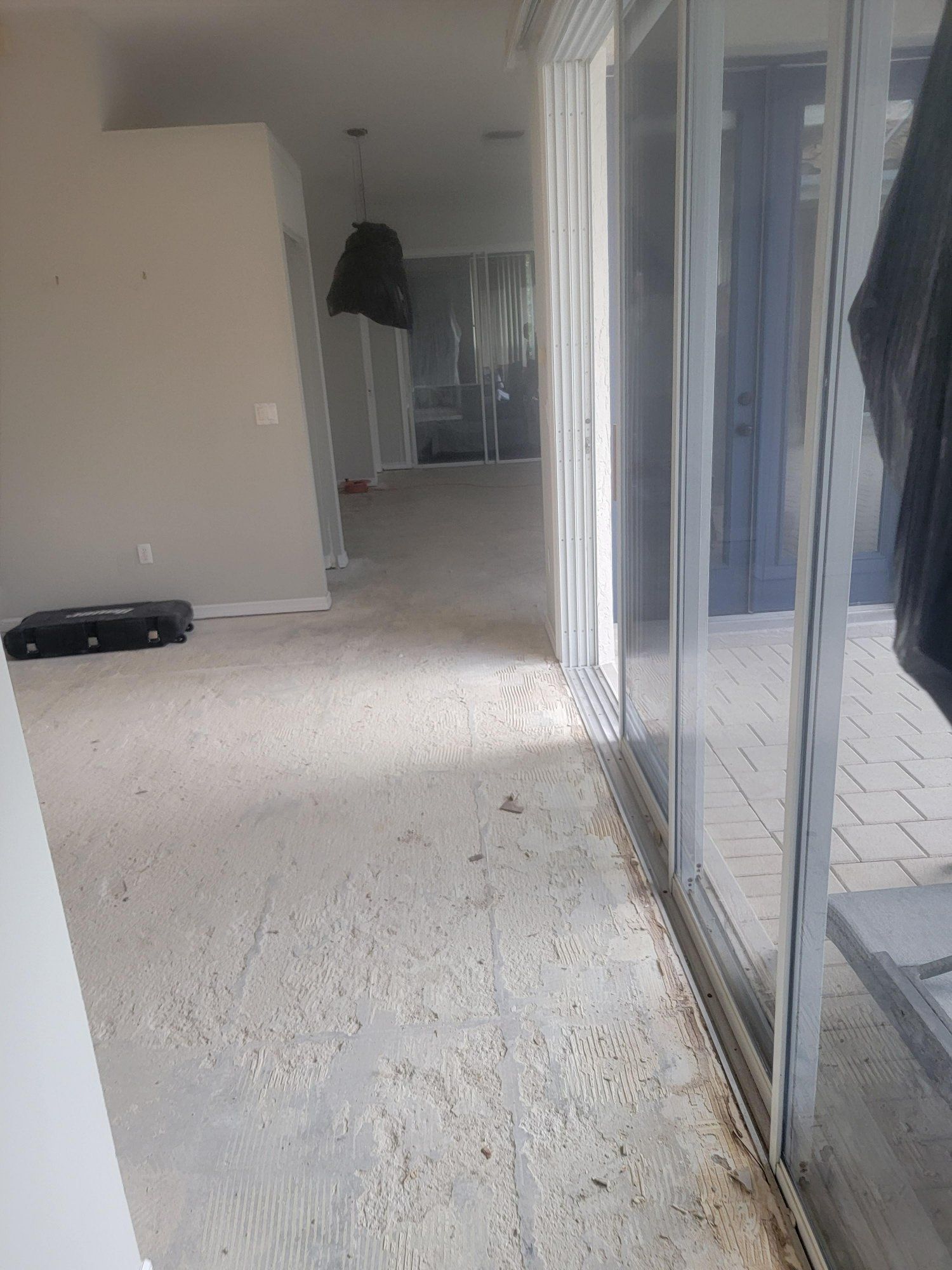 An empty room with a sliding glass door and a lamp on the floor.