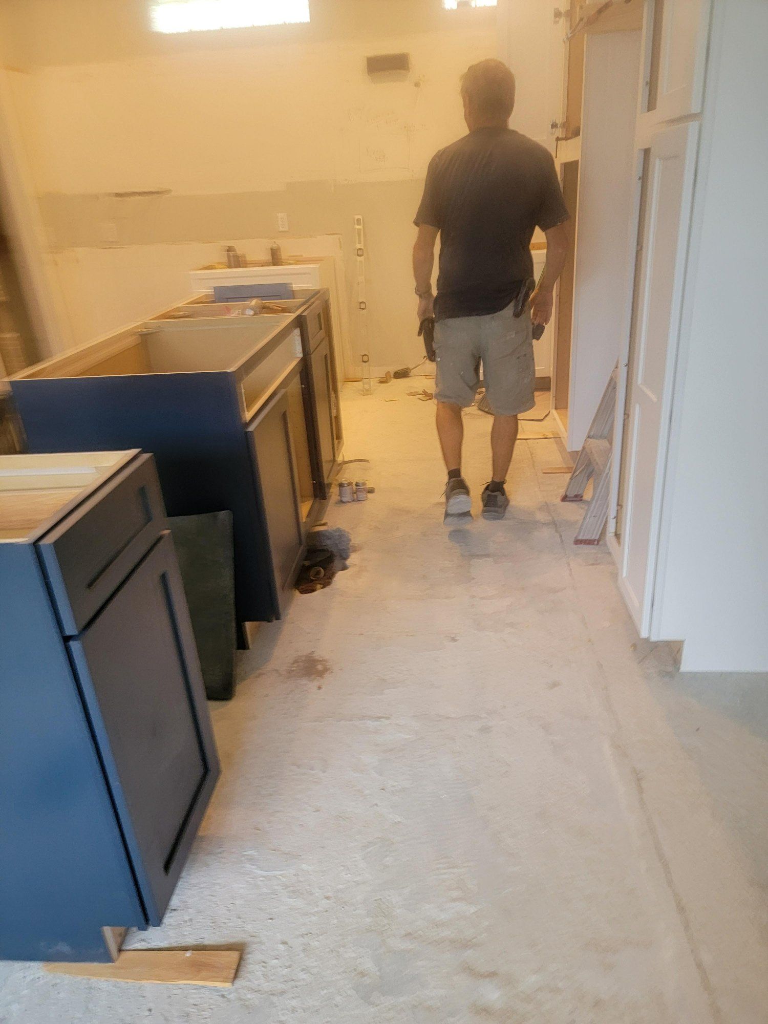 A man is walking down a hallway in a kitchen under construction.