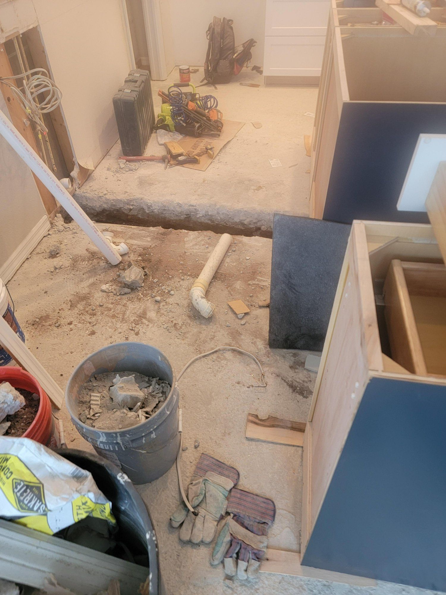 A messy room with a bucket of dirt on the floor.