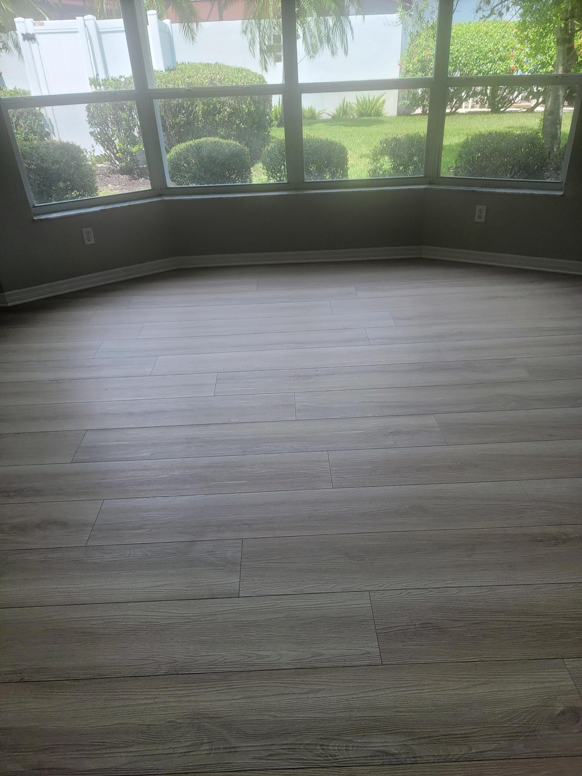 An empty room with a wooden floor and a large window.