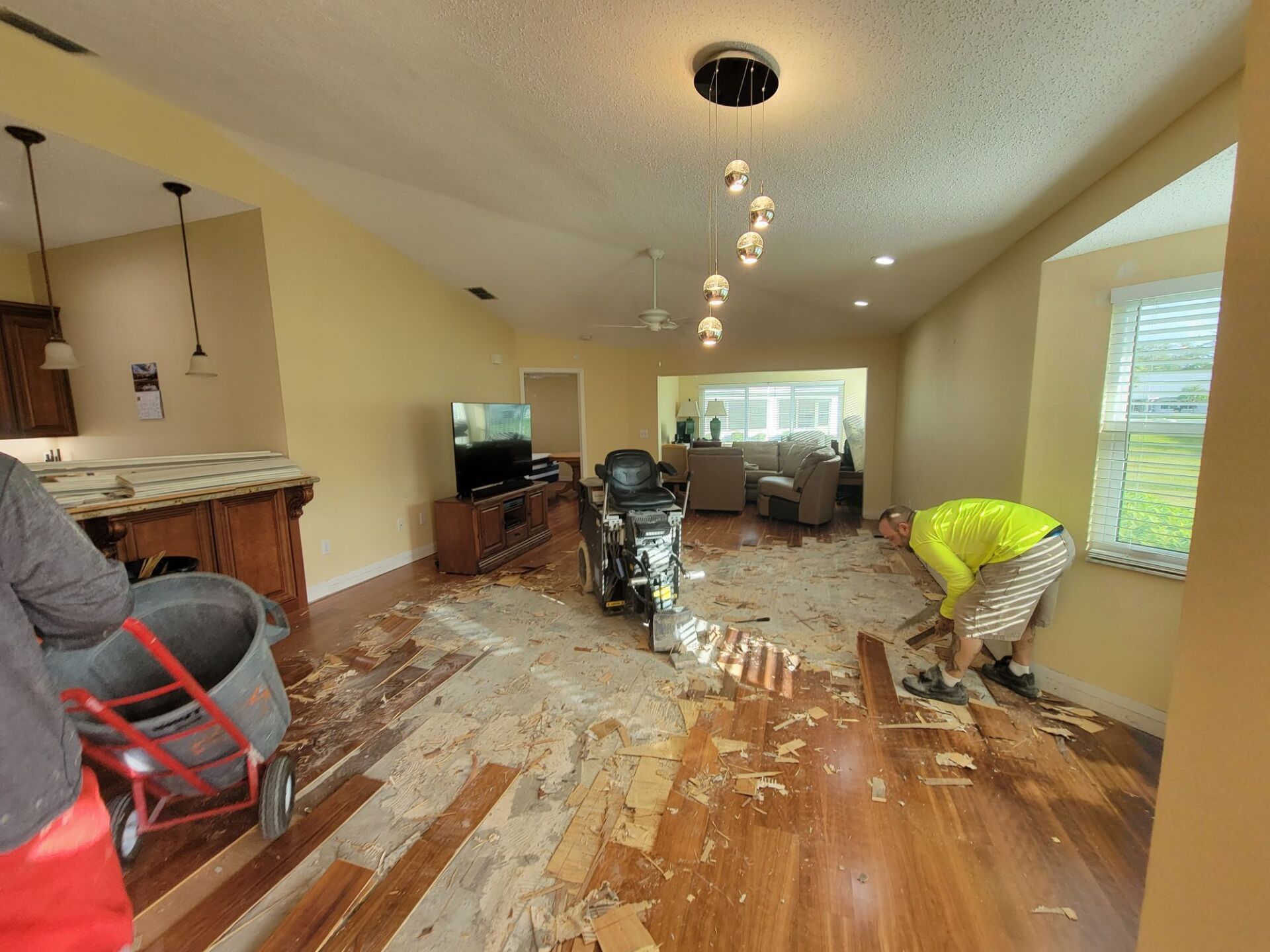 A man is working on a wooden floor in a living room.