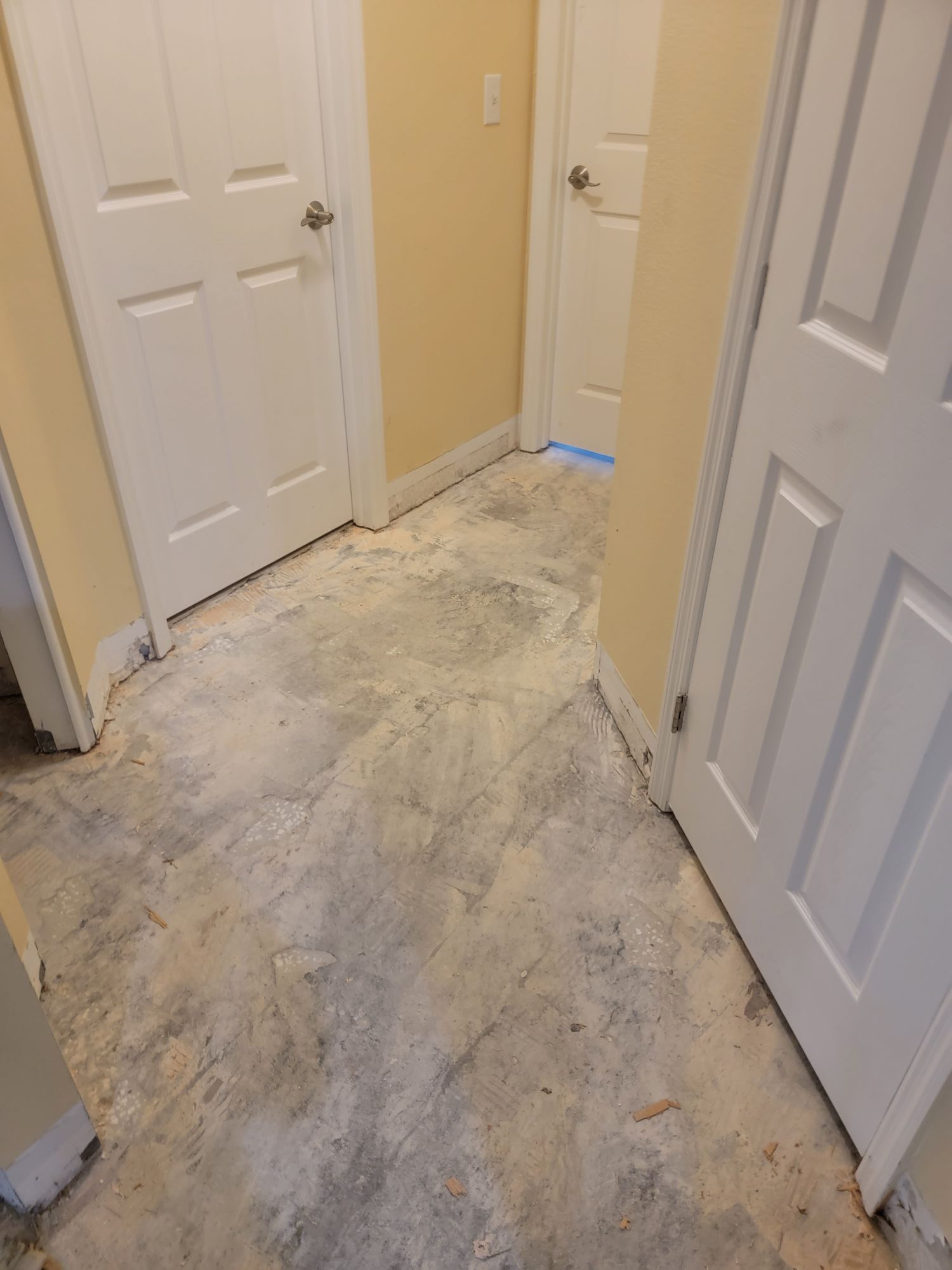 A hallway with a concrete floor and white doors.