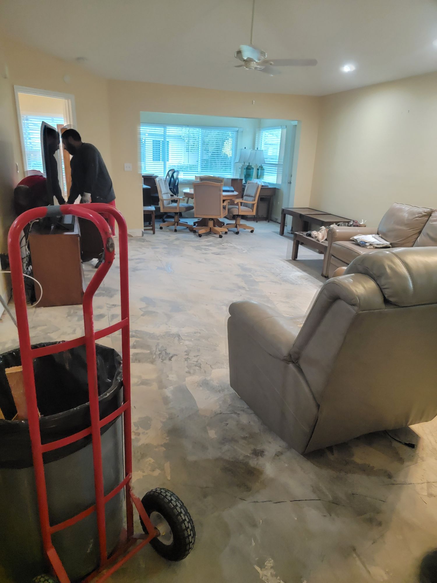 A living room with a couch , chair , table and trash can.