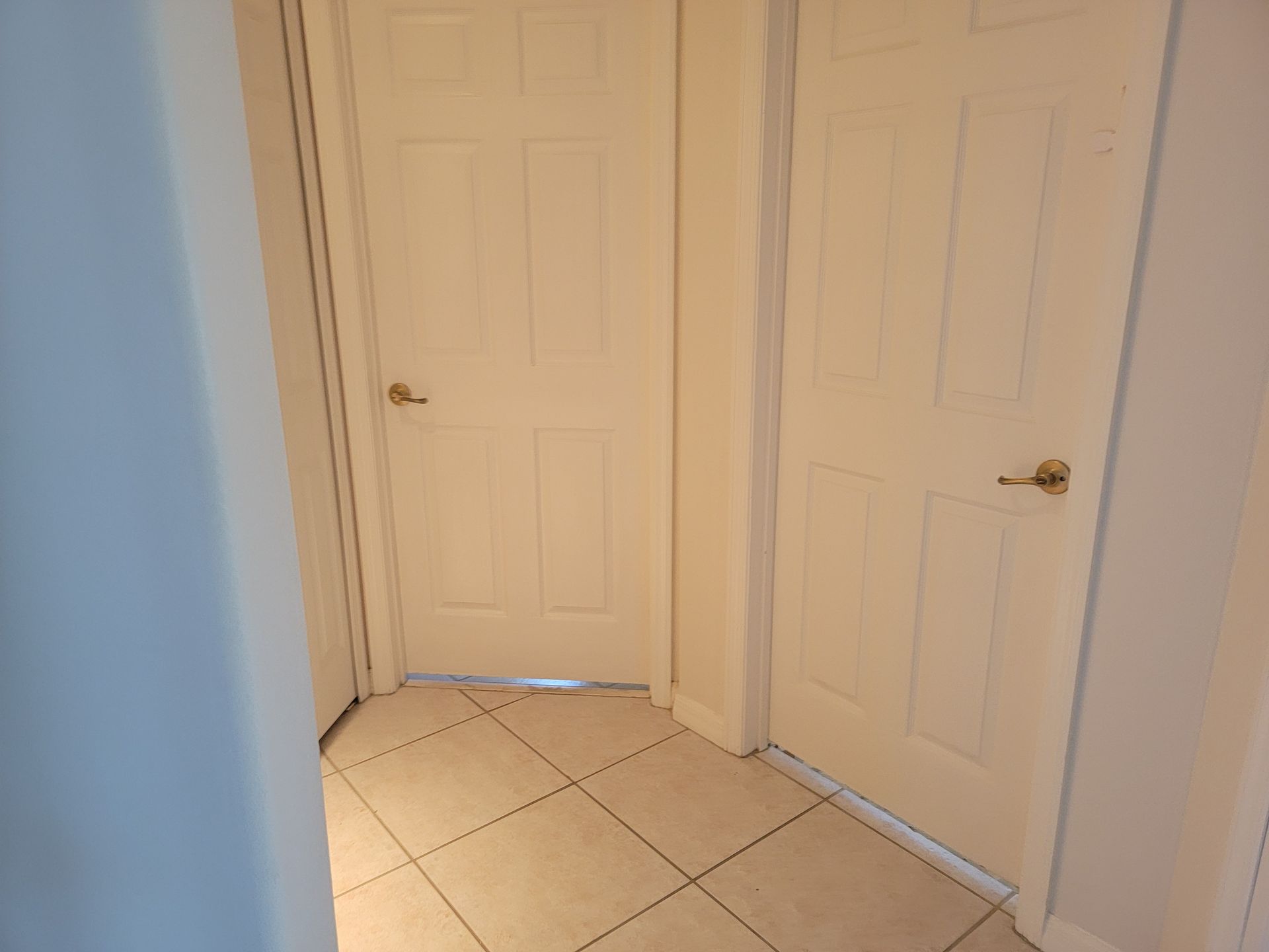A hallway with white doors and a tiled floor