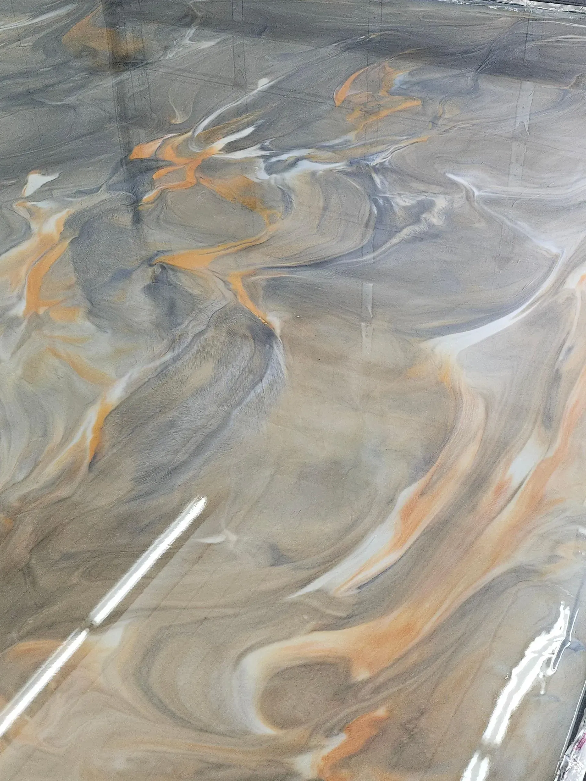 Swirling epoxy flooring in shades of gray, beige, orange, and white.