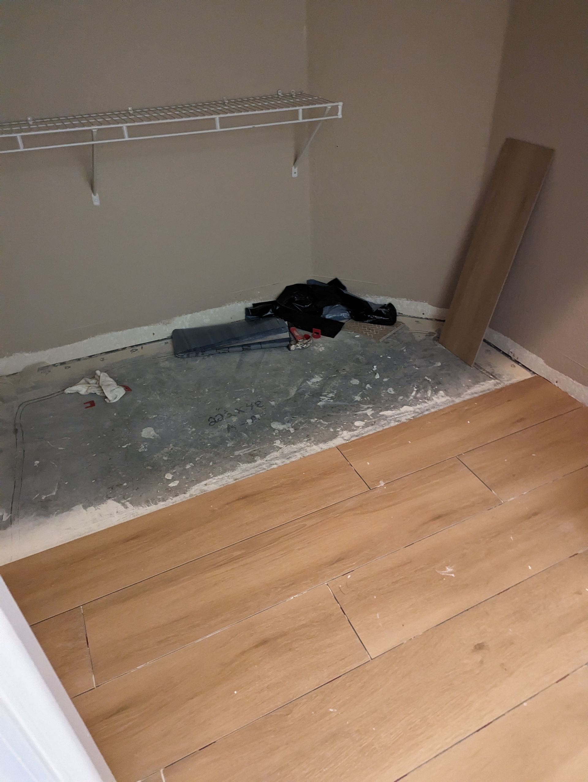 A person is laying on a wooden floor in a closet.