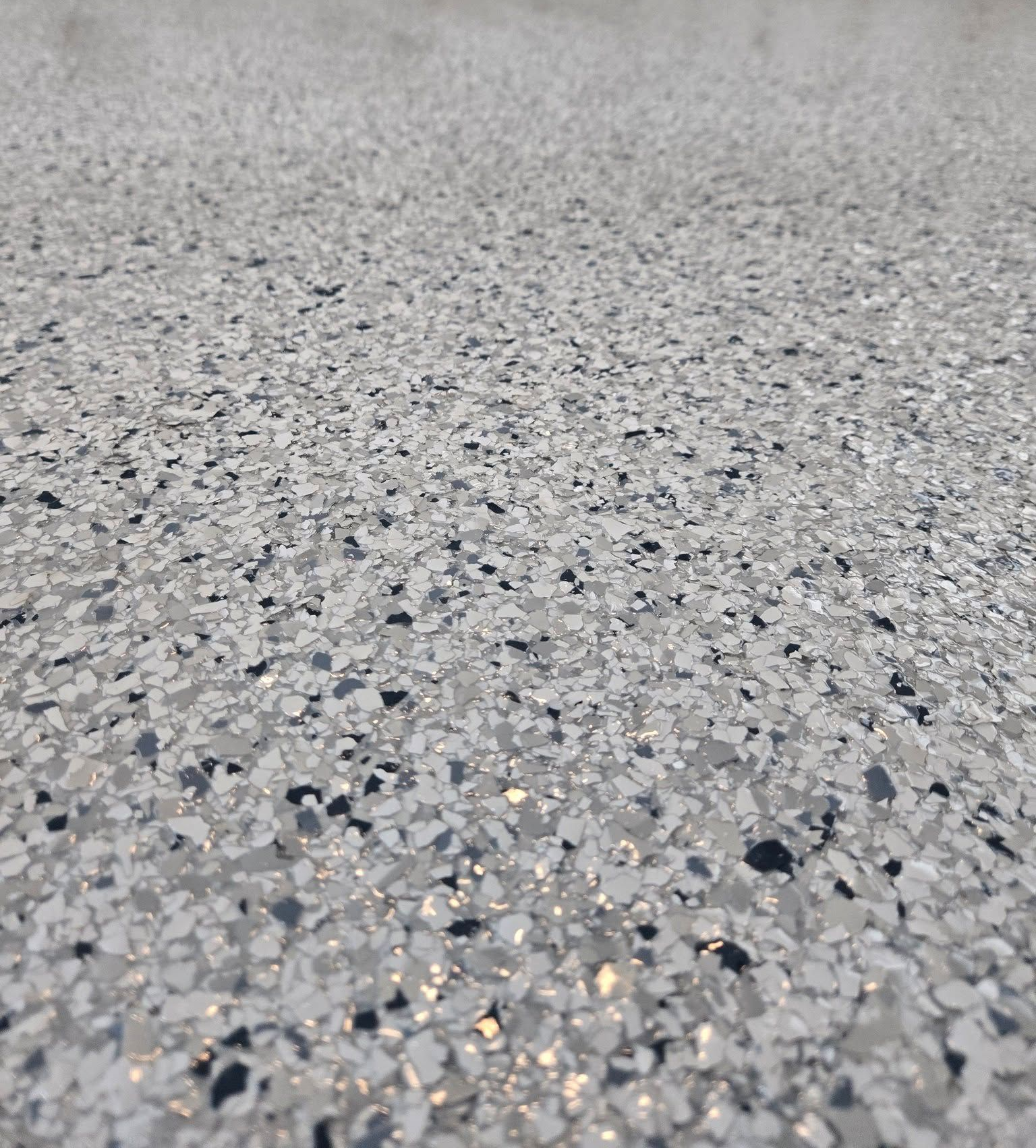 Woman in dark uniform smiles, holds papers, stands near indoor plants in a hallway.