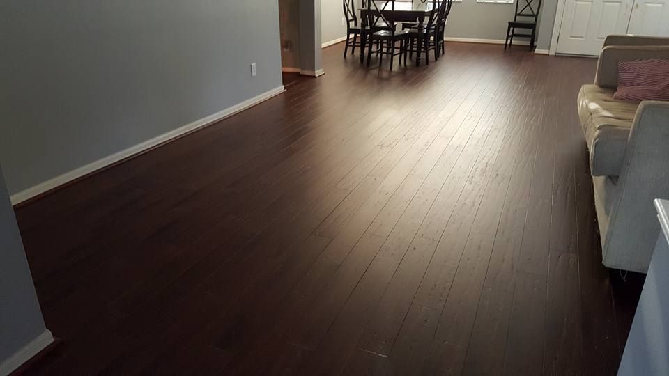 Dark hardwood floors in a living area; a dining table and sofa are visible.