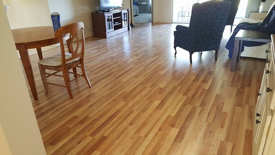 Wooden floor in a living room with a dining table, chairs, and armchairs.