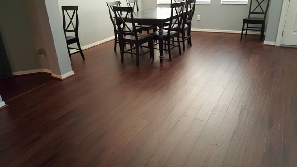 Dark wooden floor in a dining area with a table and chairs; gray walls.