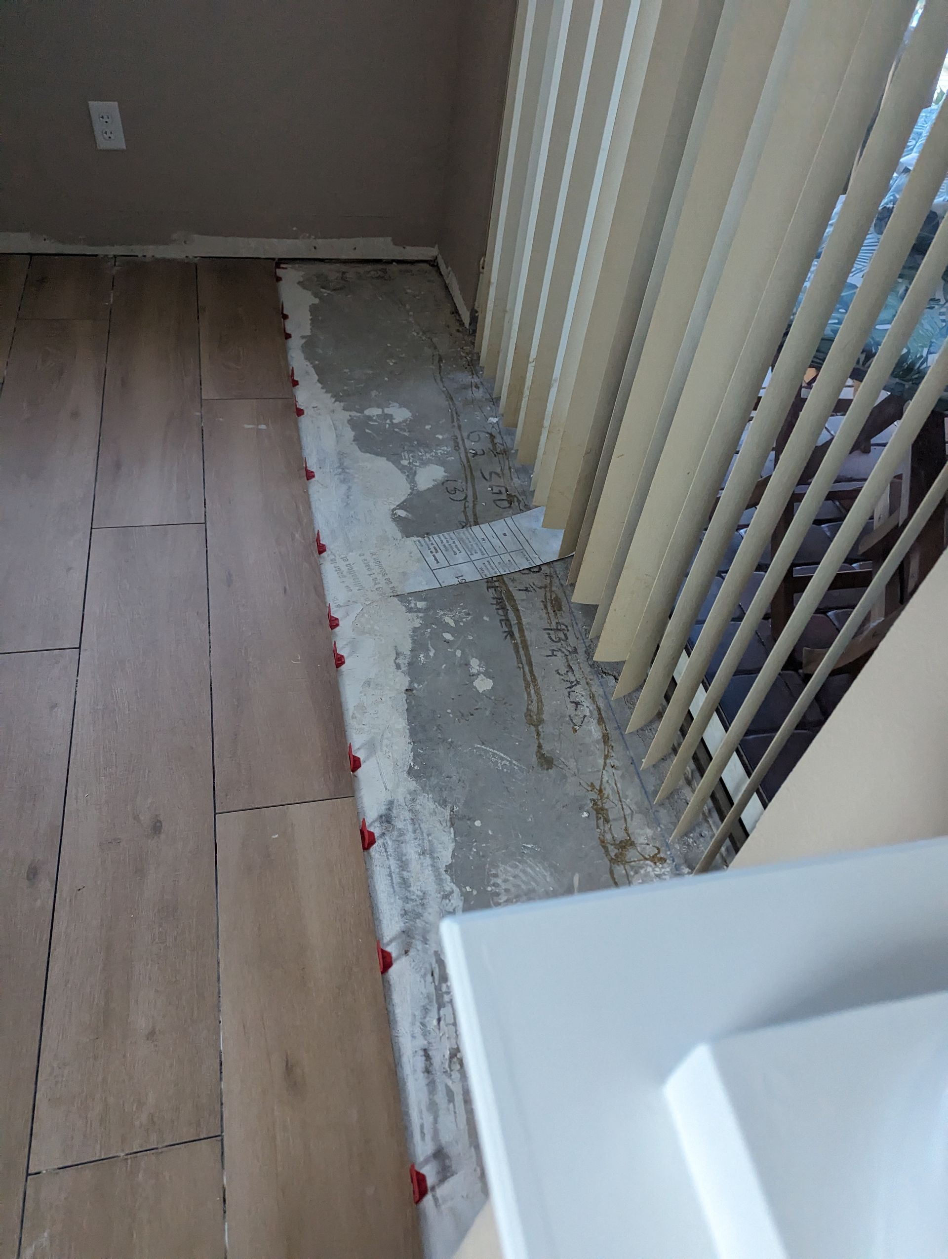 A room with a wooden floor and a window with blinds.