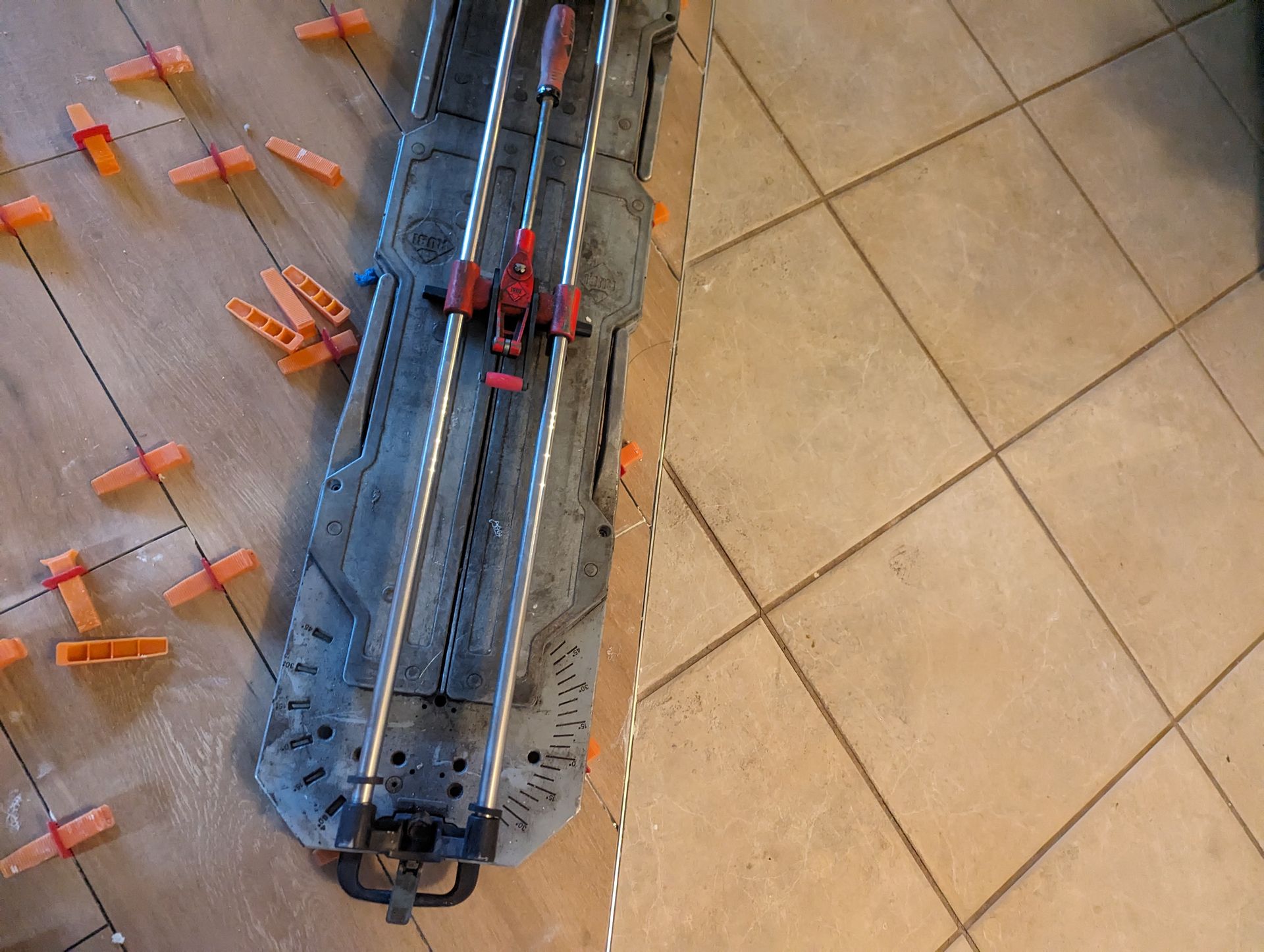 A tile cutter is sitting on a tiled floor.