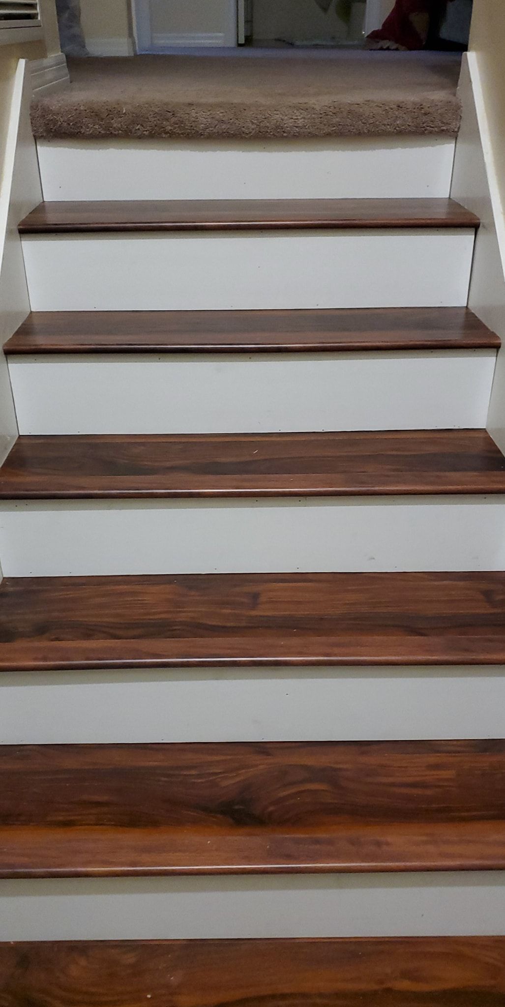 Wooden staircase with white risers and brown carpet at the top.