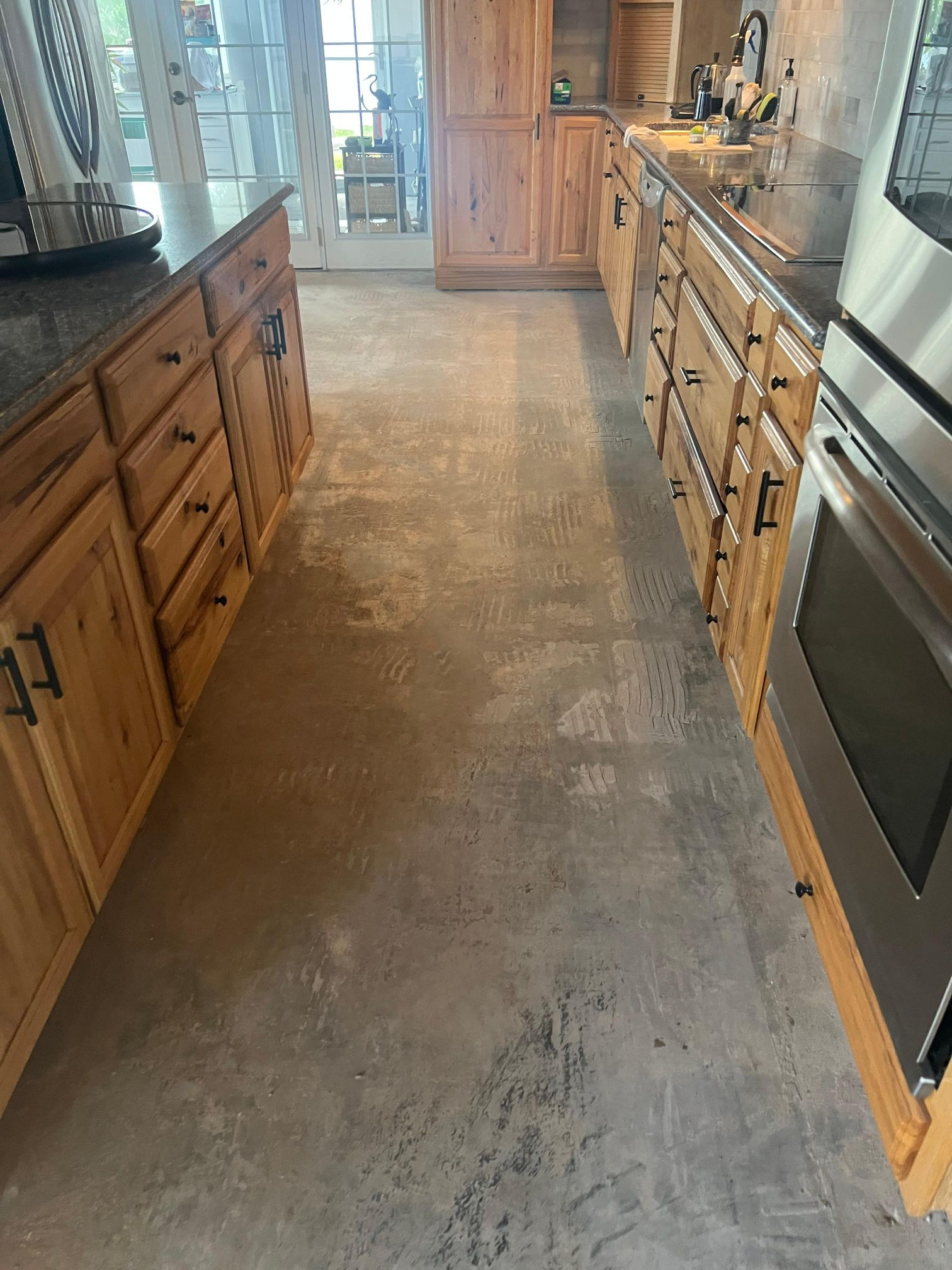 A kitchen with wooden cabinets and a concrete floor.