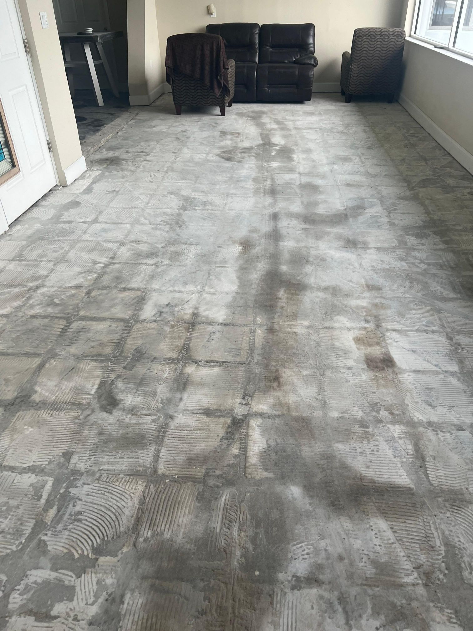 A living room with a couch and chairs and a tiled floor.