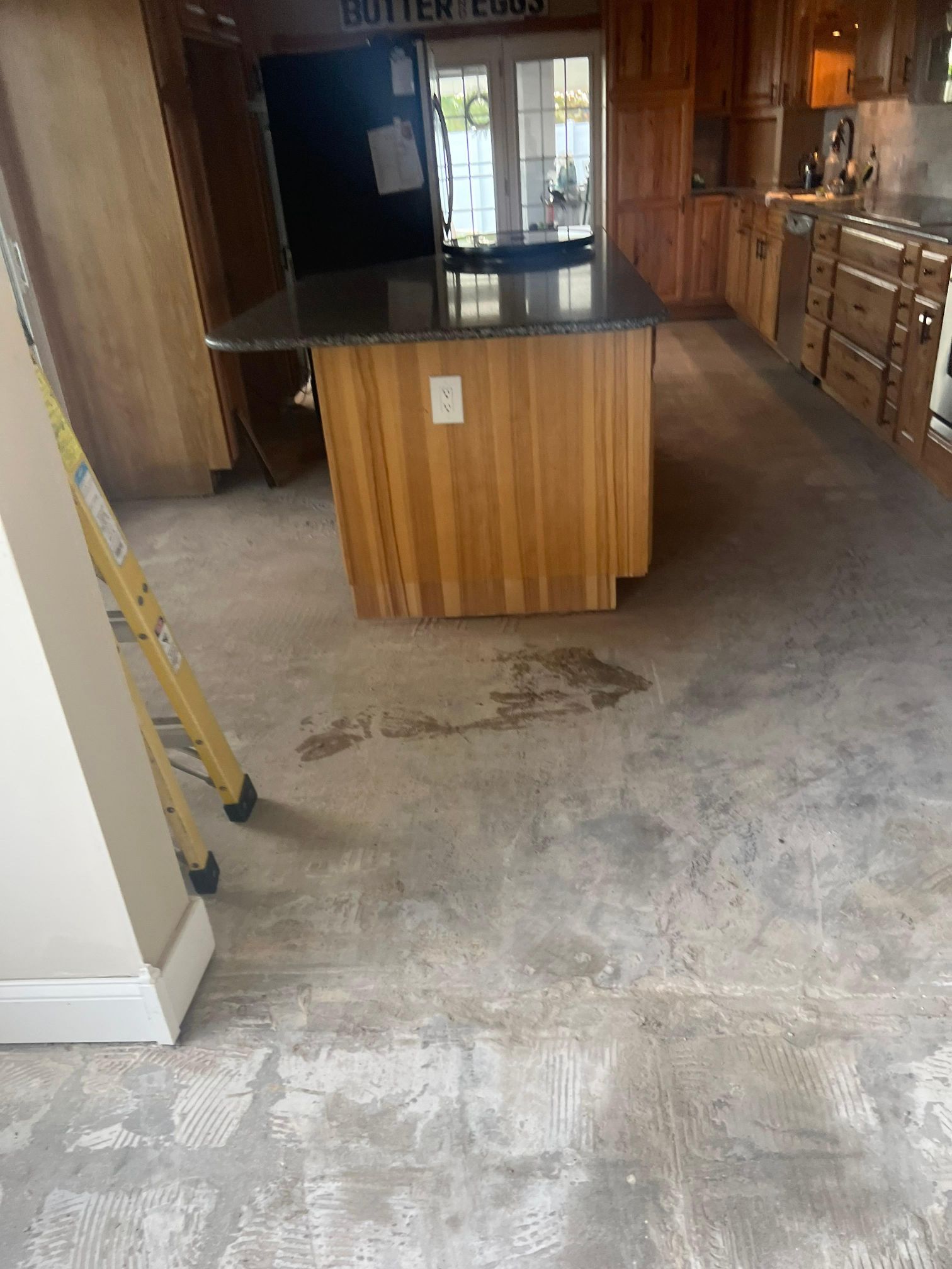 A kitchen with a wooden island and a concrete floor.