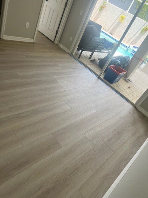 A living room with hardwood floors and a sliding glass door leading to a pool.