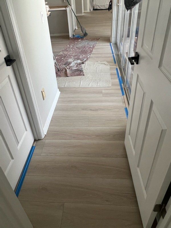 A hallway with hardwood floors and white doors is being painted.