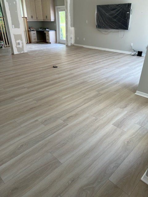 A living room with a wooden floor and a flat screen tv on the wall.