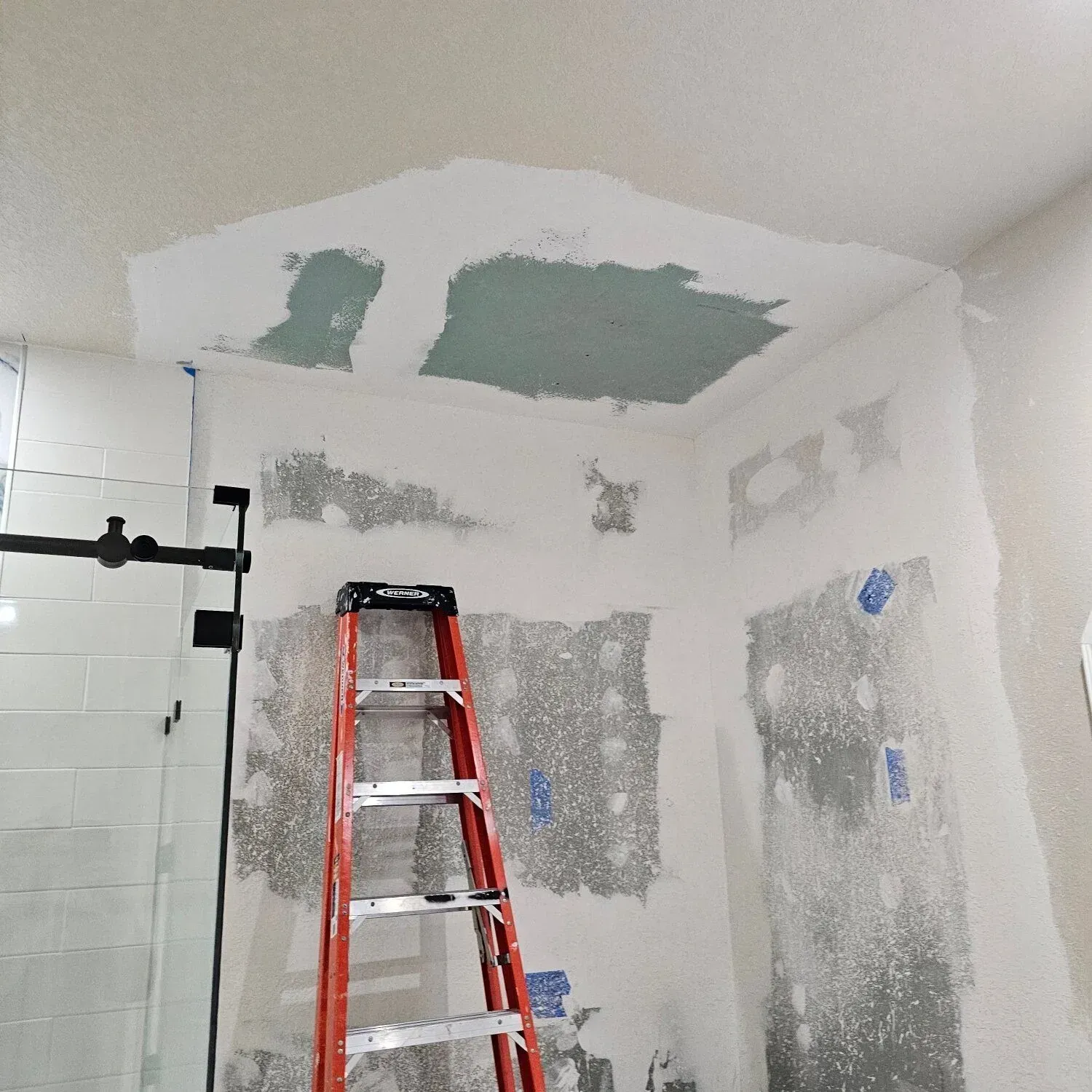 Bathroom interior under construction with a ladder and exposed drywall.