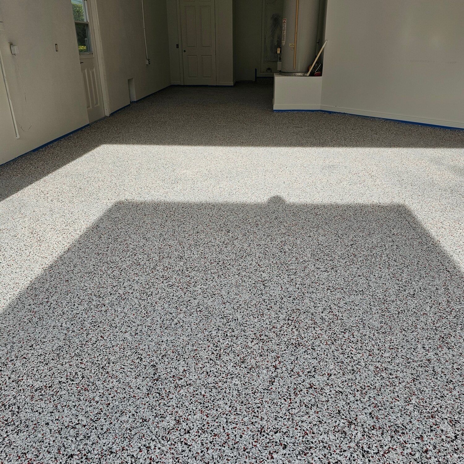 A garage floor with a shadow of a broom on it.