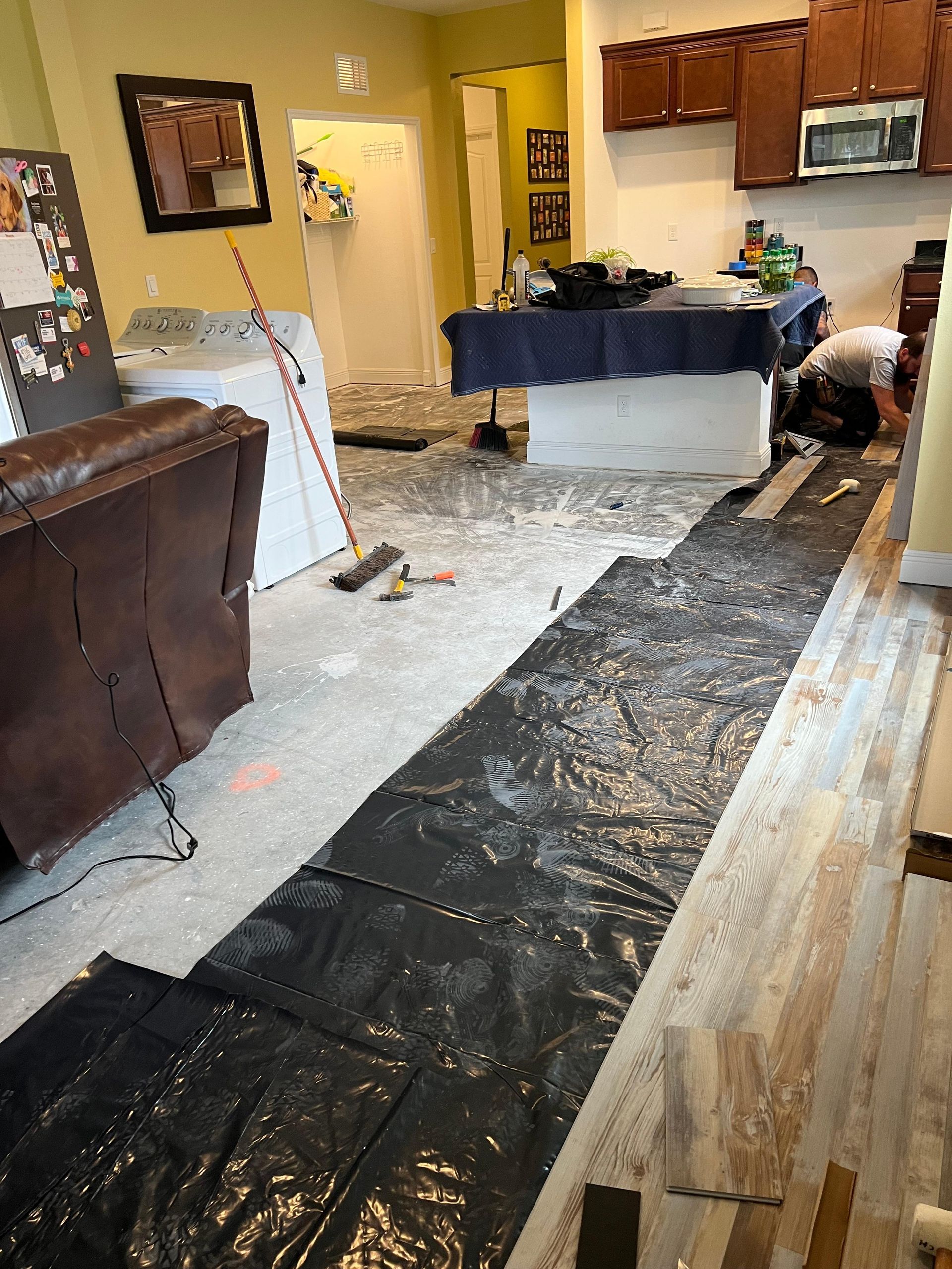 A kitchen is being remodeled with a black tarp on the floor.