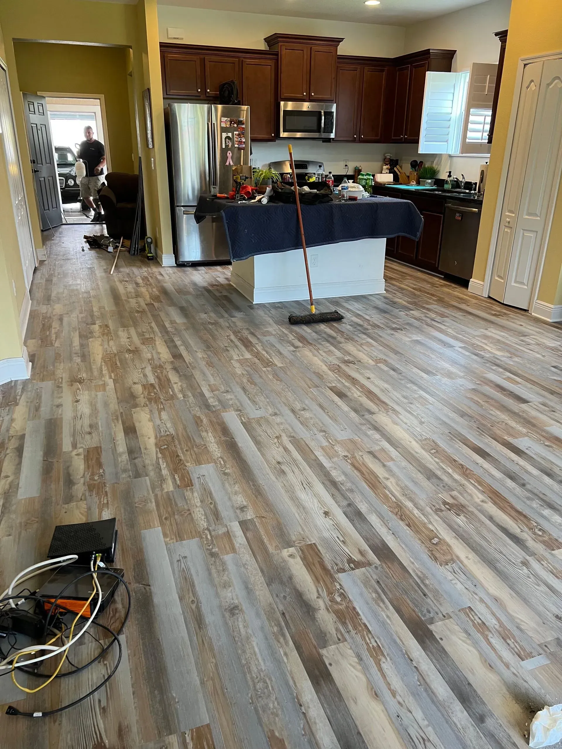 Wooden floor in a kitchen with a central island and dark cabinets.
