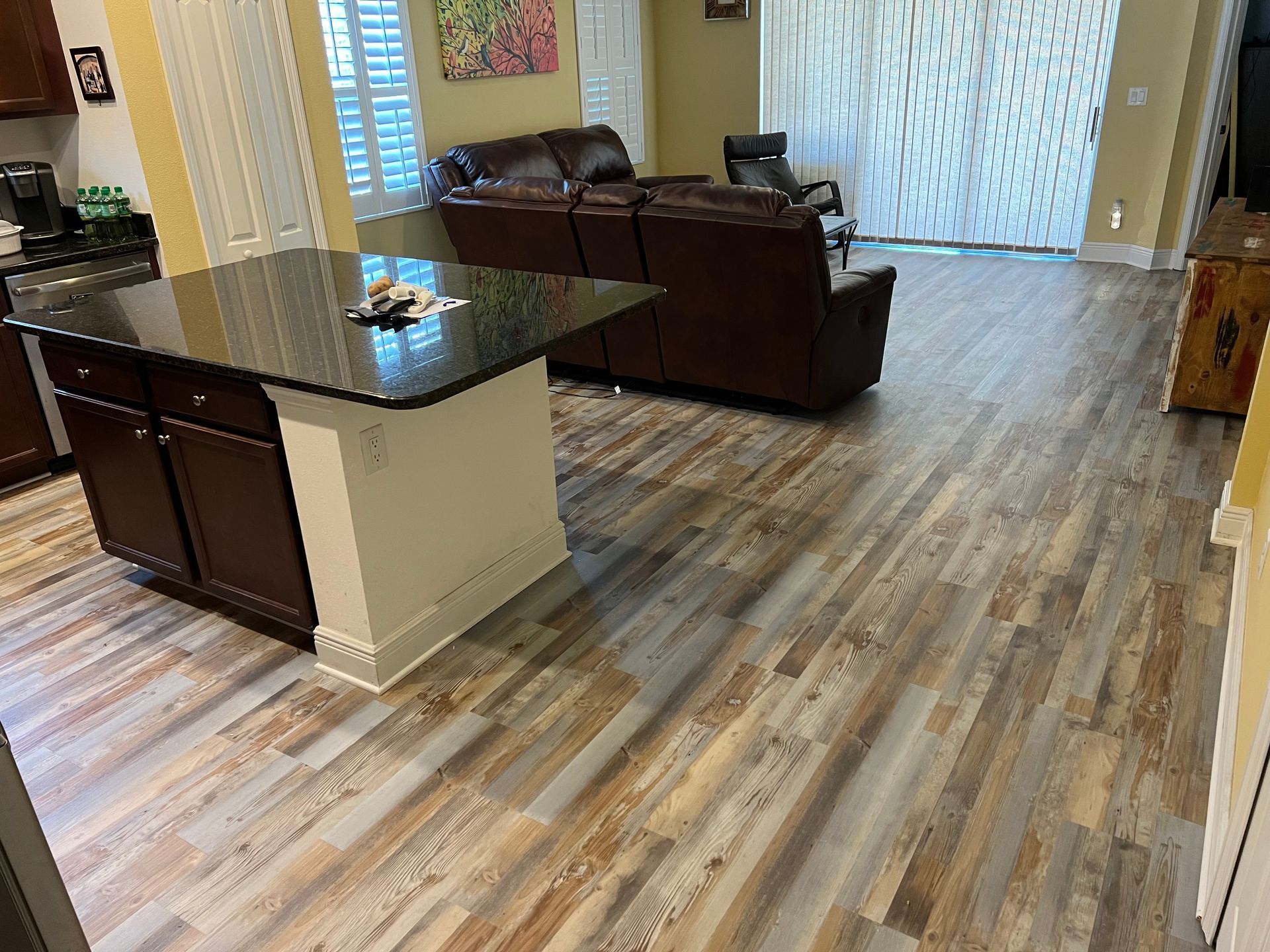A living room with hardwood floors , a couch , and a kitchen.