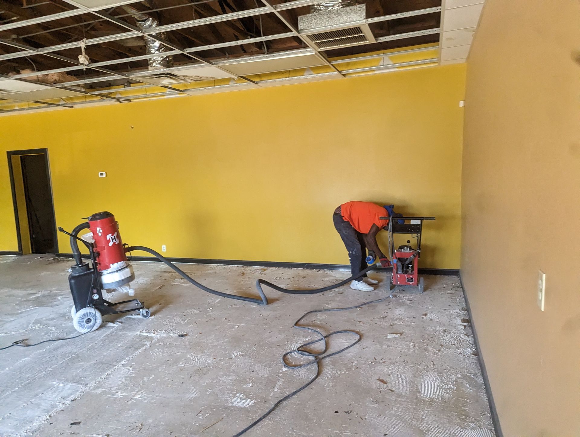 A man is using a vacuum cleaner in an empty room.